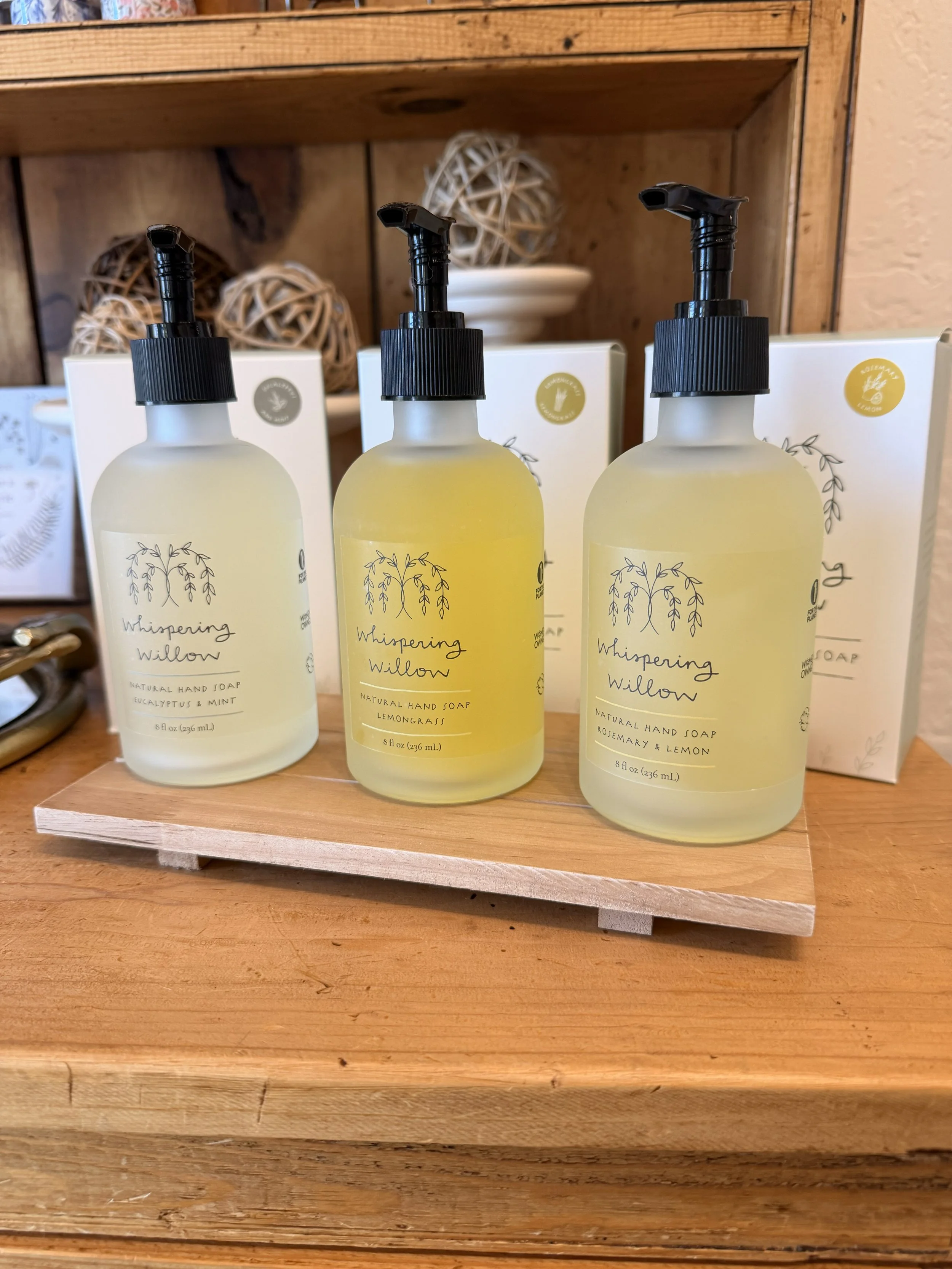 Whispering Willow's Rosemary and Lemon Natural Pump Hand Soap on display with two other bottles at Bloomie's Boutique