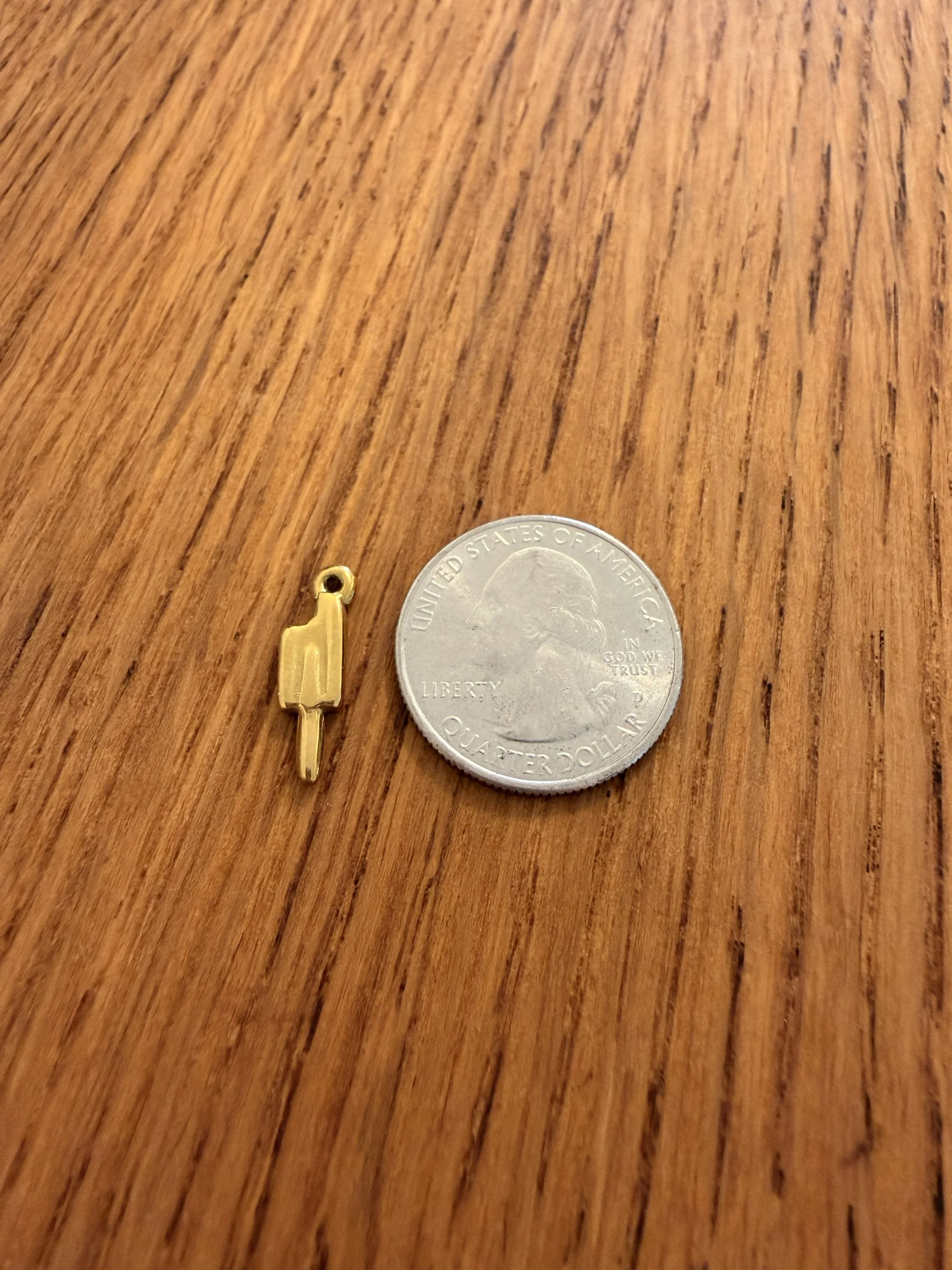 Popsicle Charm by House of Azelea with quarter on wood countertop