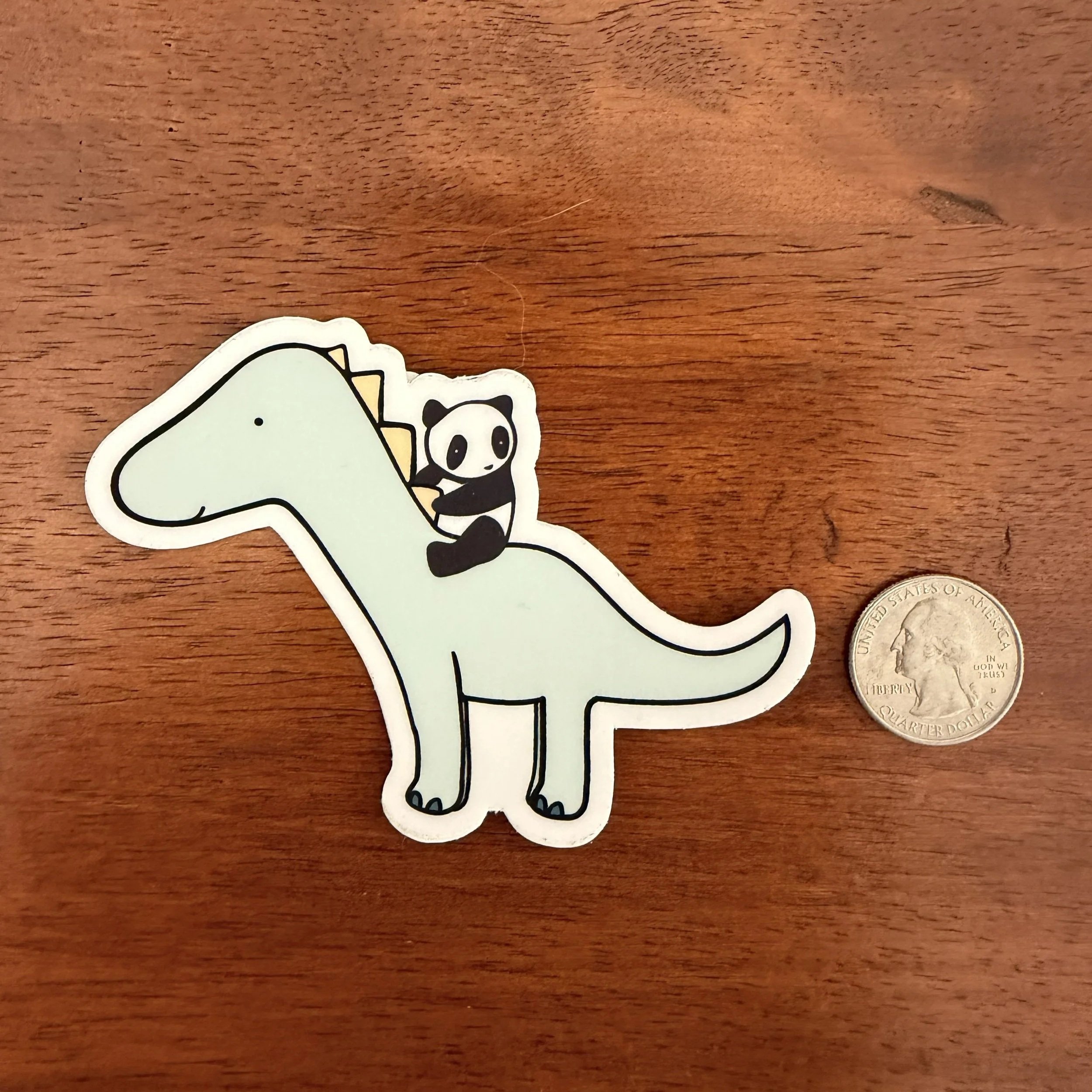 Panda Riding Dinosaur Vinyl Sticker with quarter and wood background
