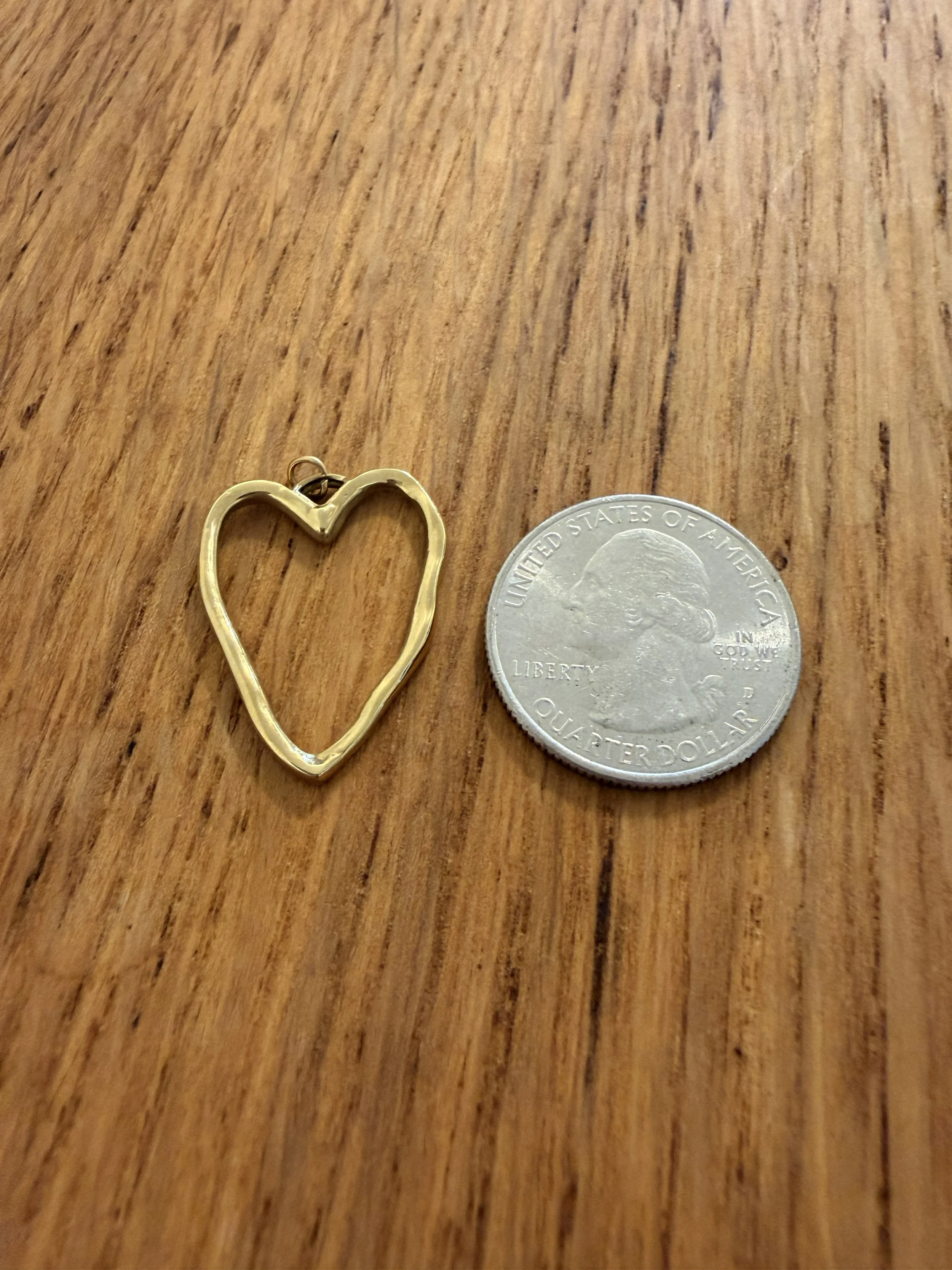 Hammered Heart Outline Pendant by House of Azelea with quarter on wood countertop