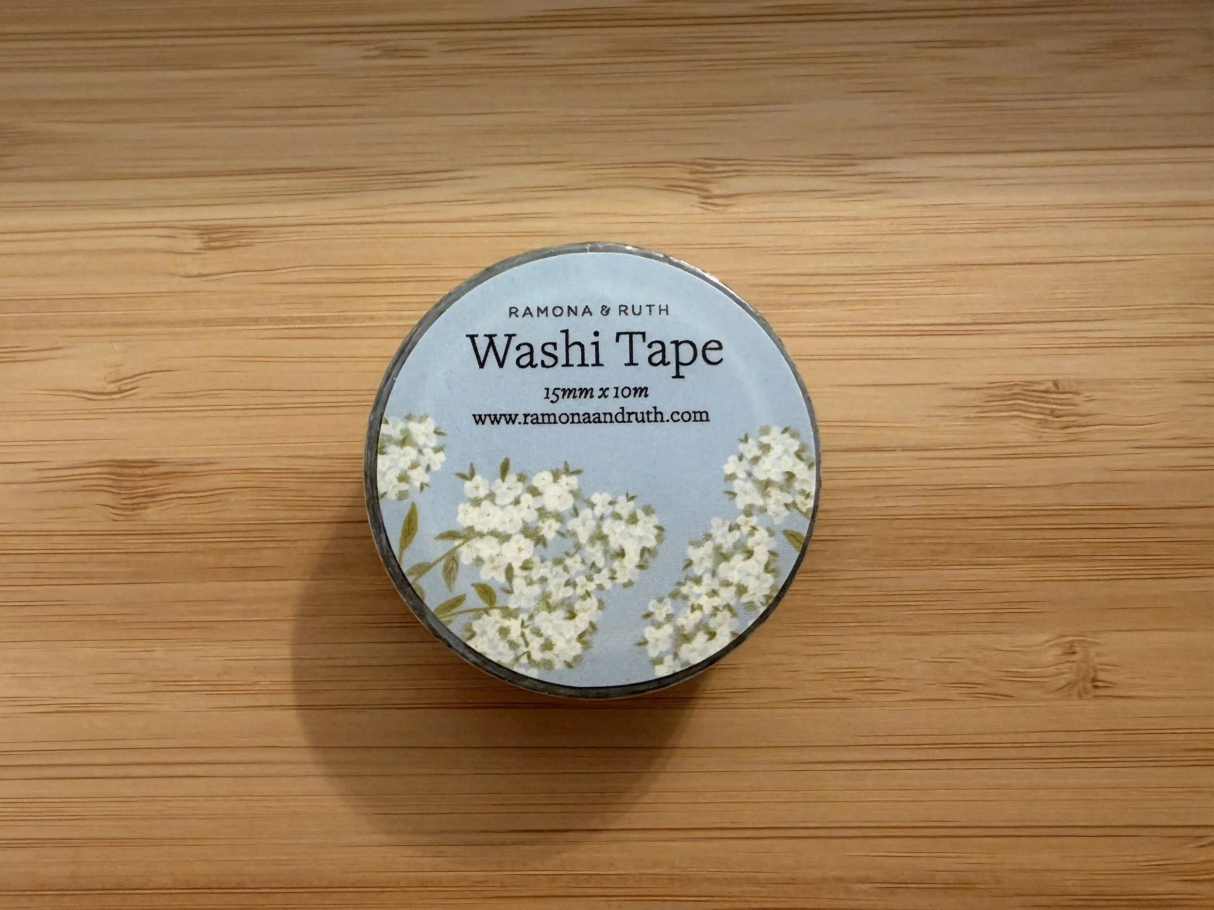 One roll of Ramona & Ruth's Hydrangea Washi Tape laying flat on bamboo