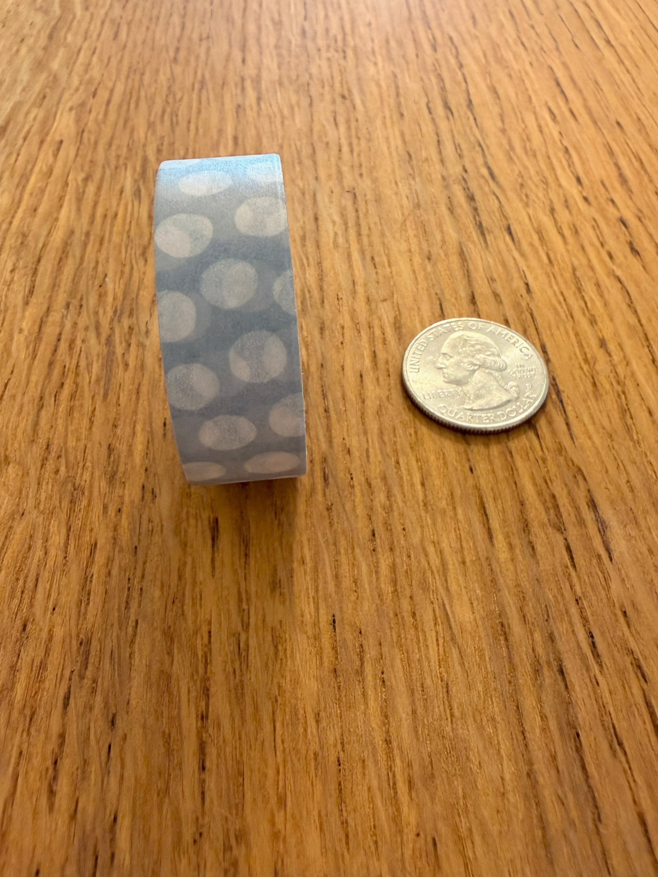One roll of Ramona & Ruth's Soft Dots Washi Tape on edge with quarter on wood countertop