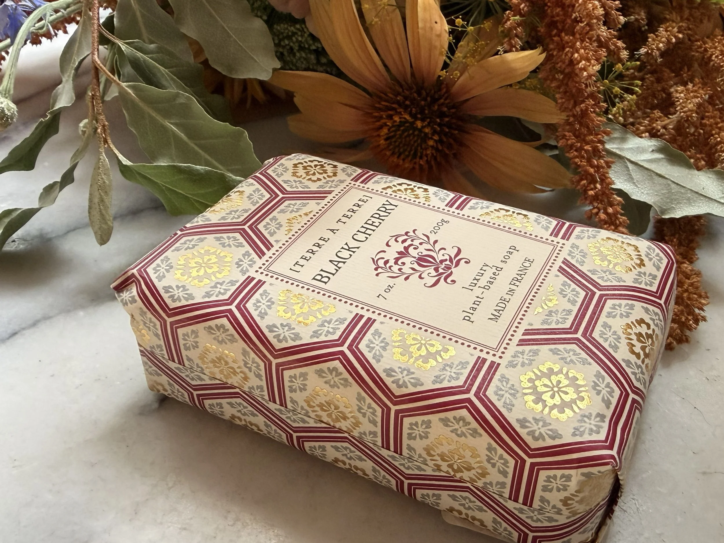 Side view of Terre à Terre Black Cherry Soap with flowers on marble