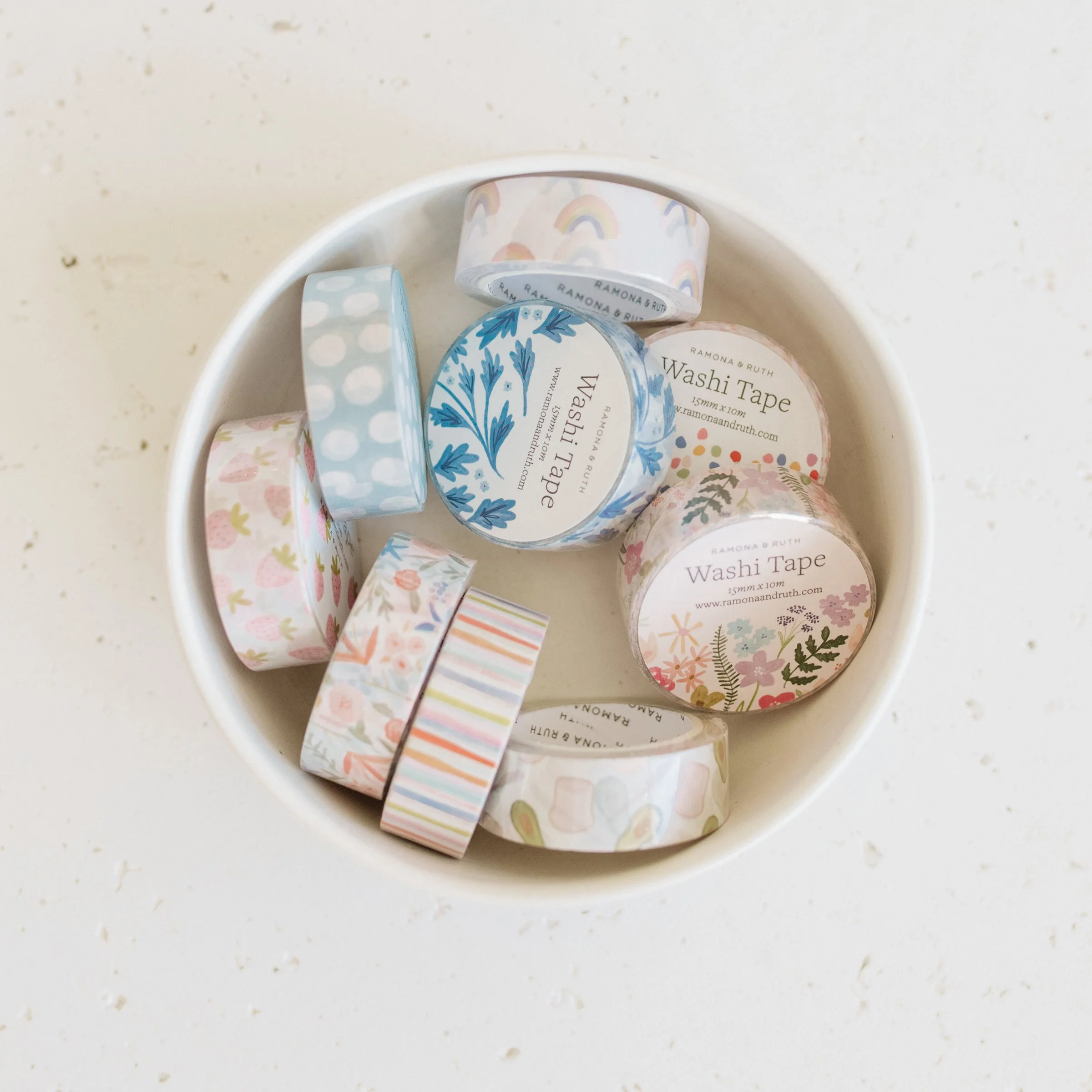 Bowl full of various washi tape rolls by Ramona & Ruth including Strawberry Washi Tape, Soft Dots Washi Tape, Blue Vines Washi Tape, Rainbows Washi Tape, Spicy Floral Washi Tape, among others