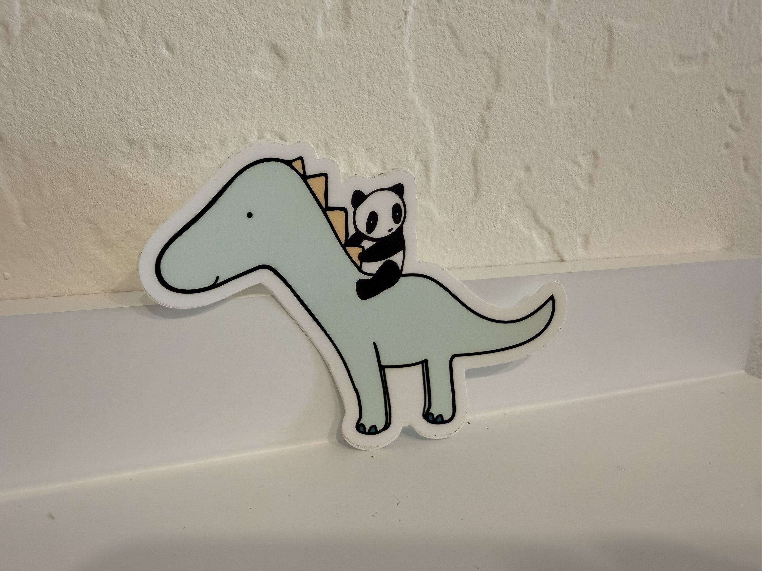 Panda Riding Dinosaur Vinyl Sticker on white shelf
