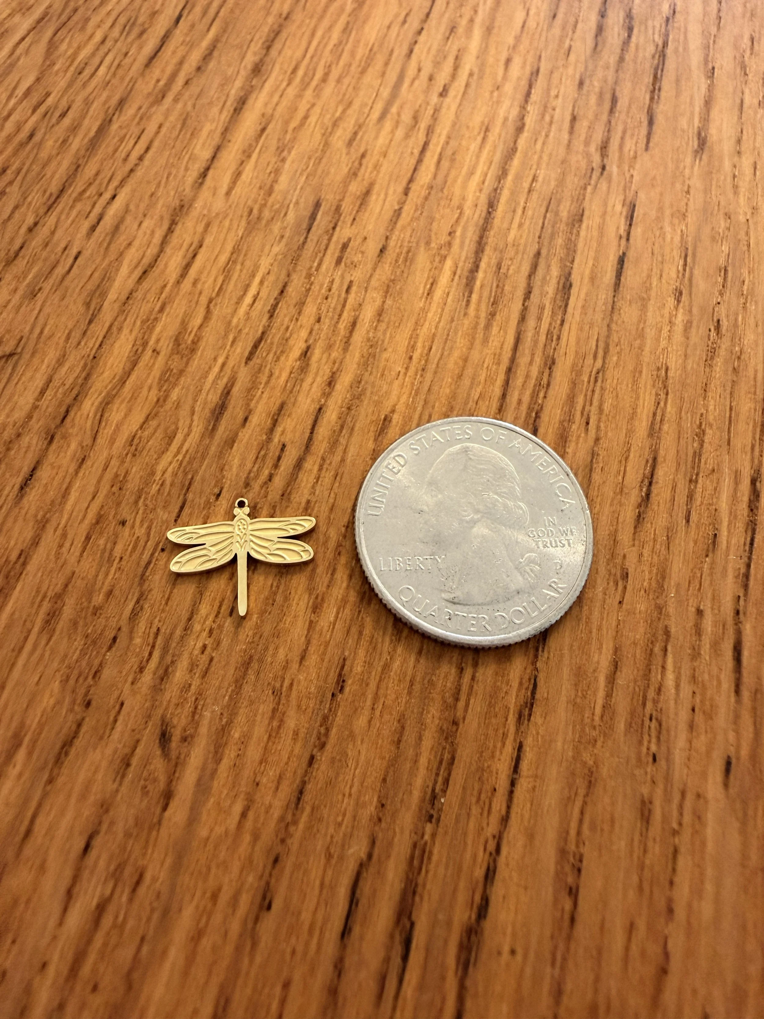 Dragonfly Charm by House of Azelea with quarter on wood countertop