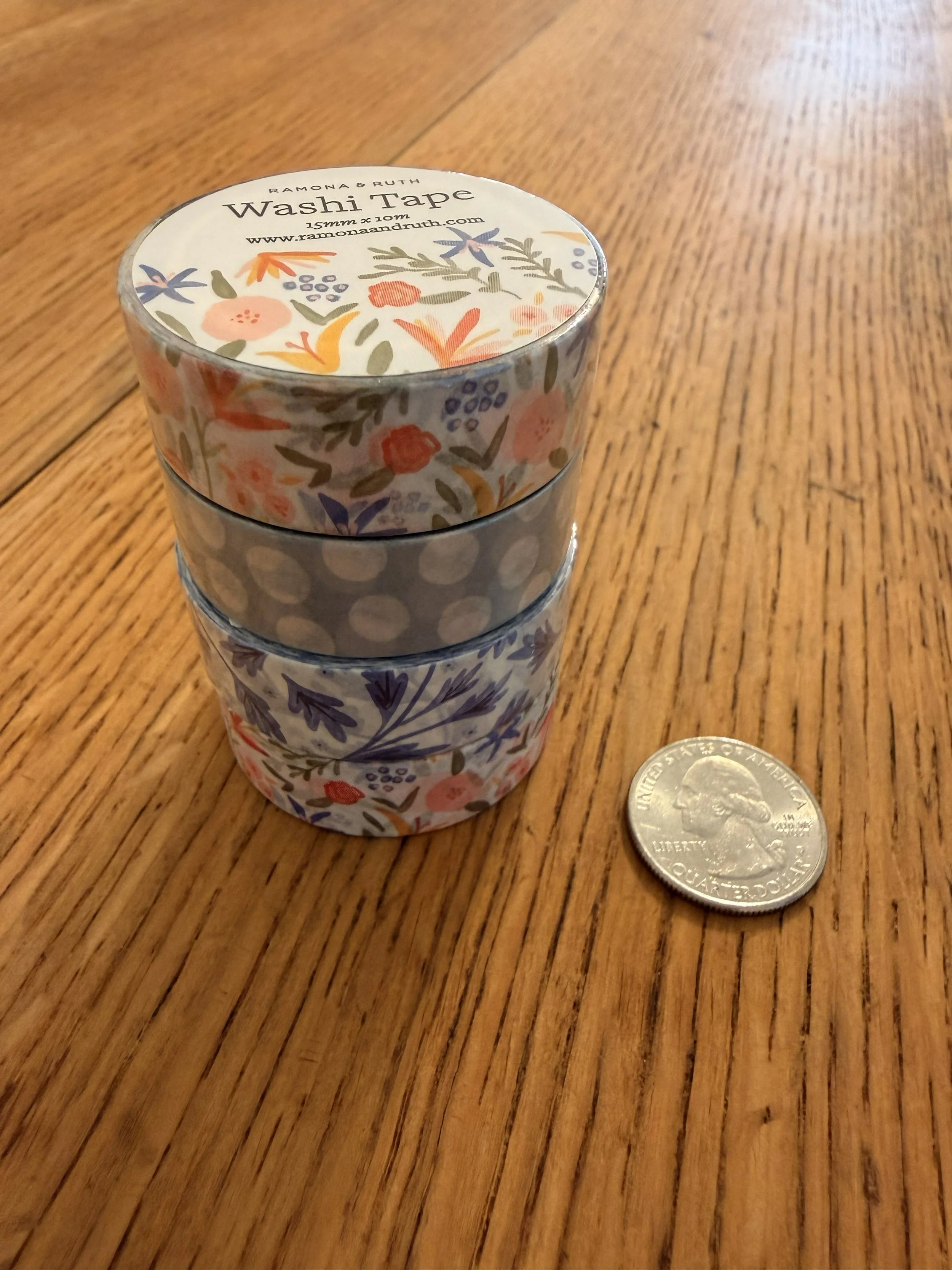 Stack of Ramona & Ruth's Spicy Floral Washi Tape, Soft Dots Washi Tape, and Blue Vines Washi Tape with quarter on wood countertop