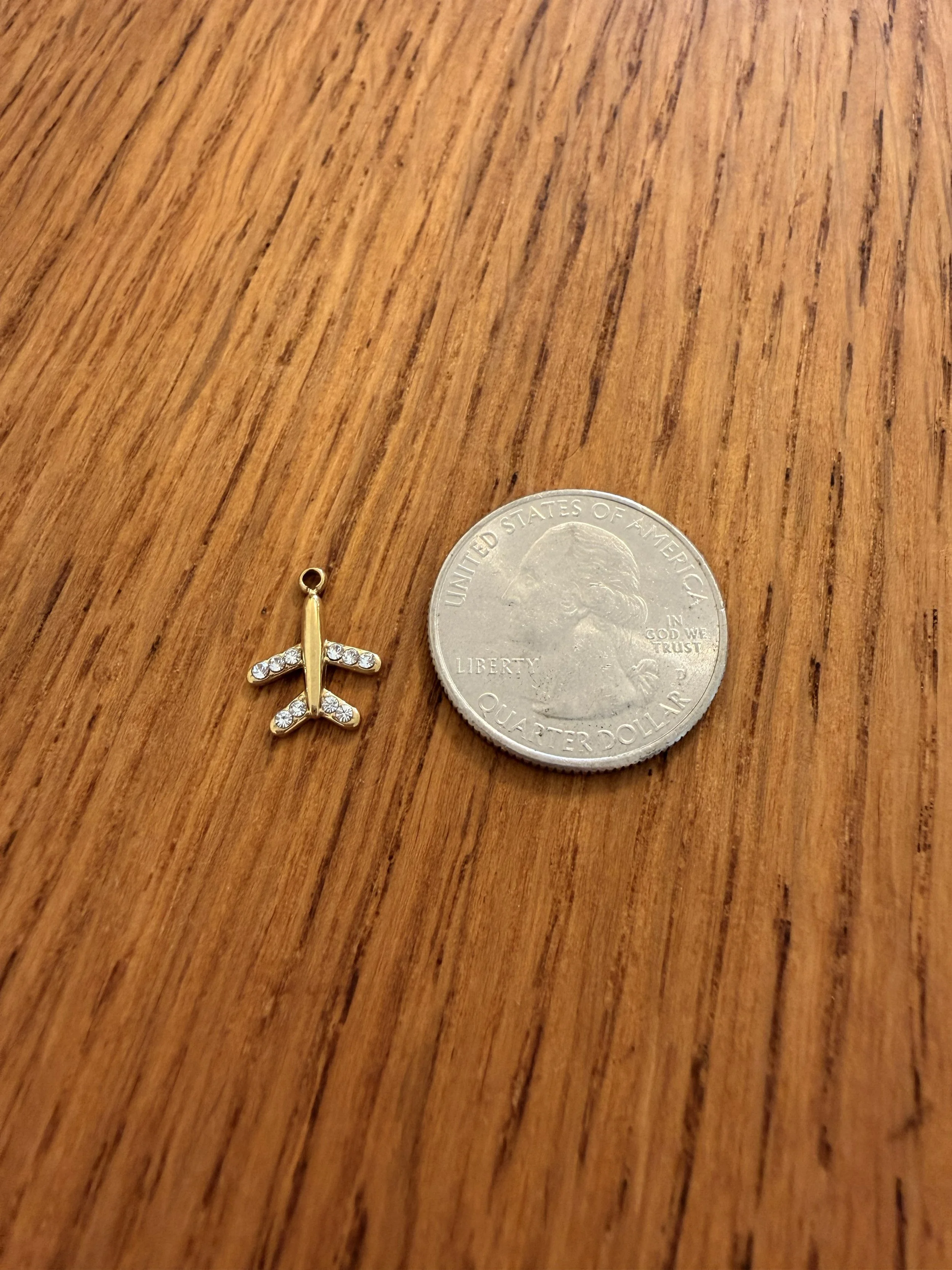 Airplane Charm by House of Azelea with quarter on wood countertop