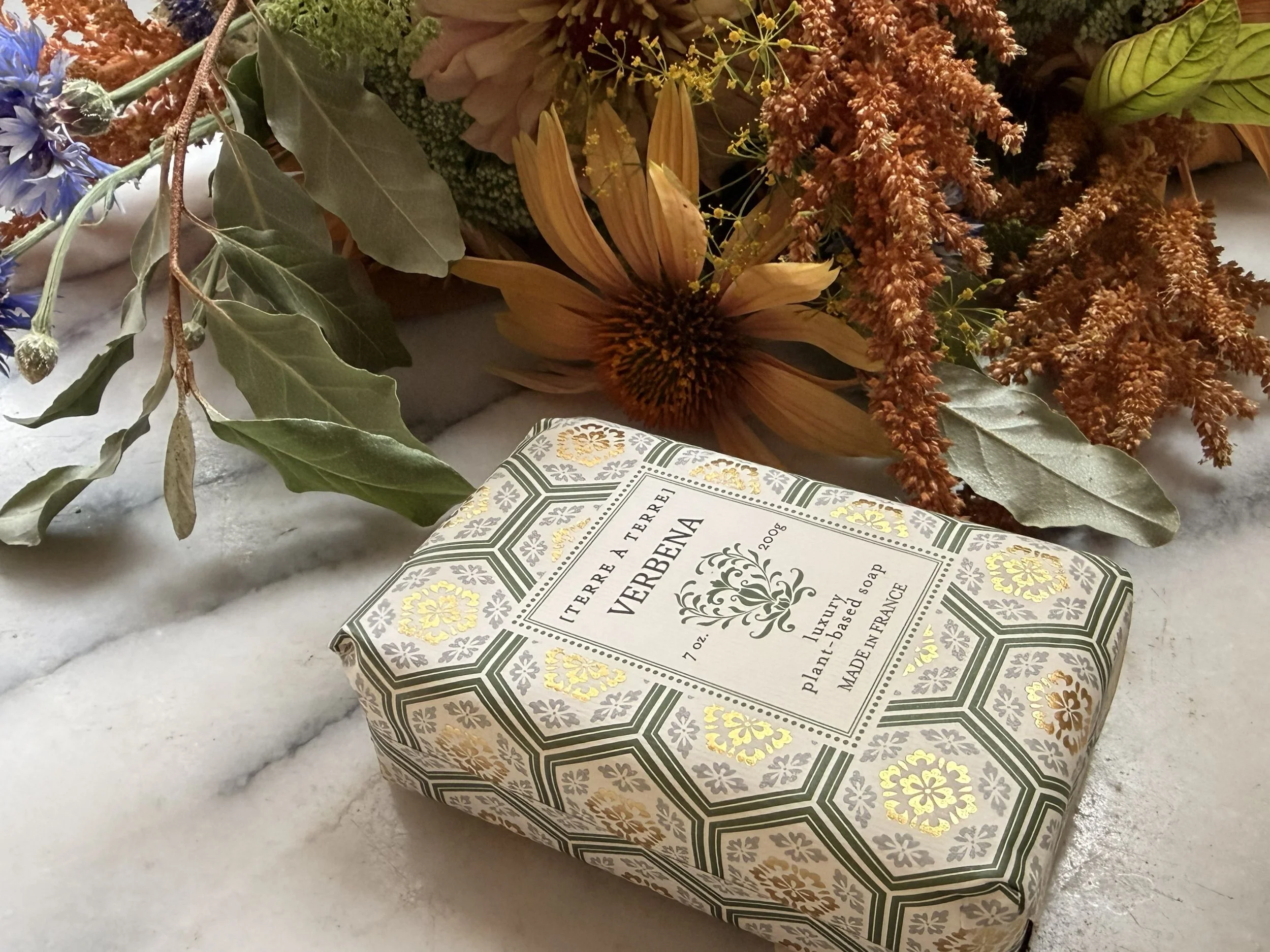 Side view of Terre á Terre Verbena Soap on marble with flowers