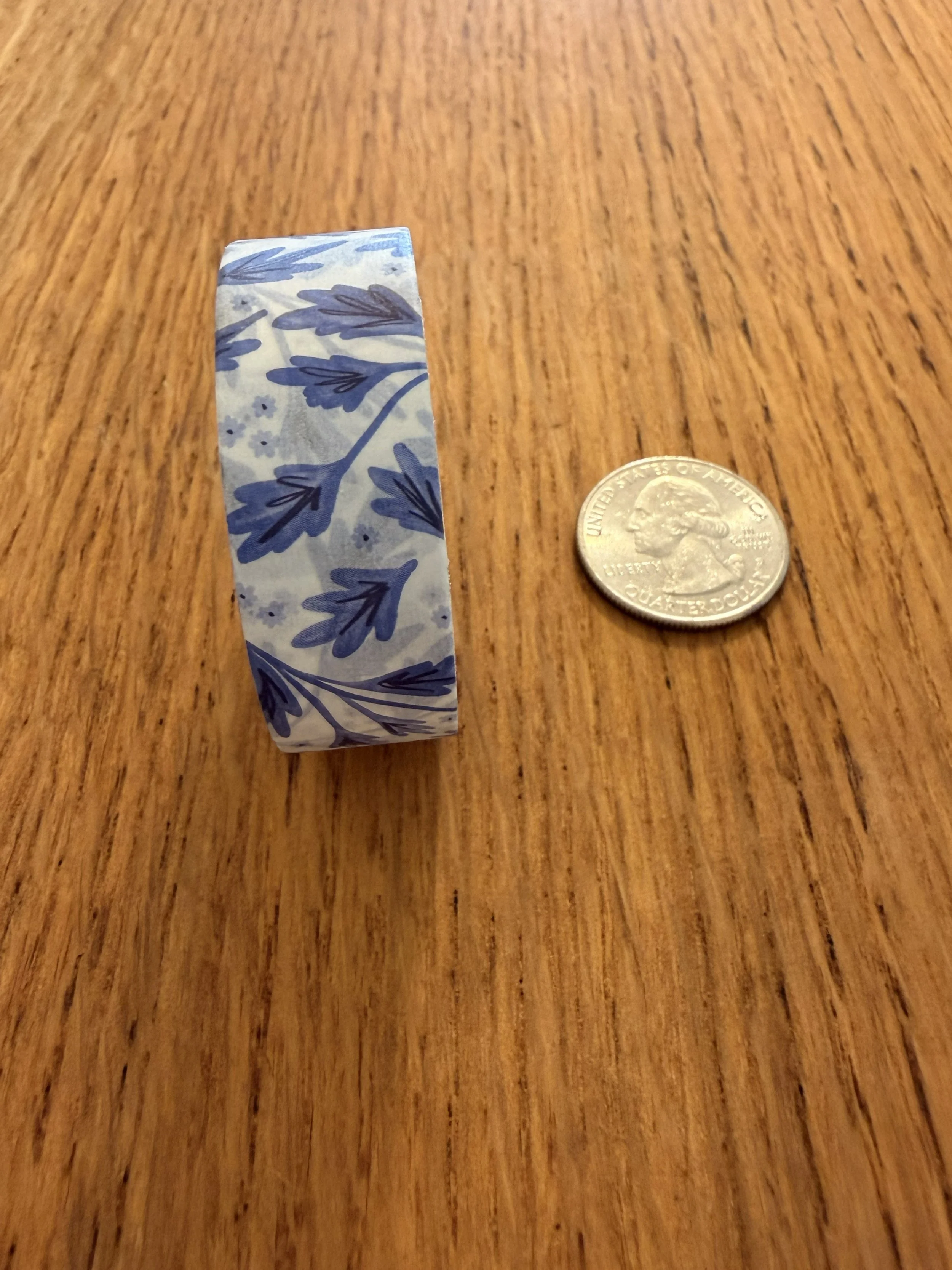 One roll of Ramona & Ruth's Blue Vines Washi Tape on edge with quarter on wood countertop