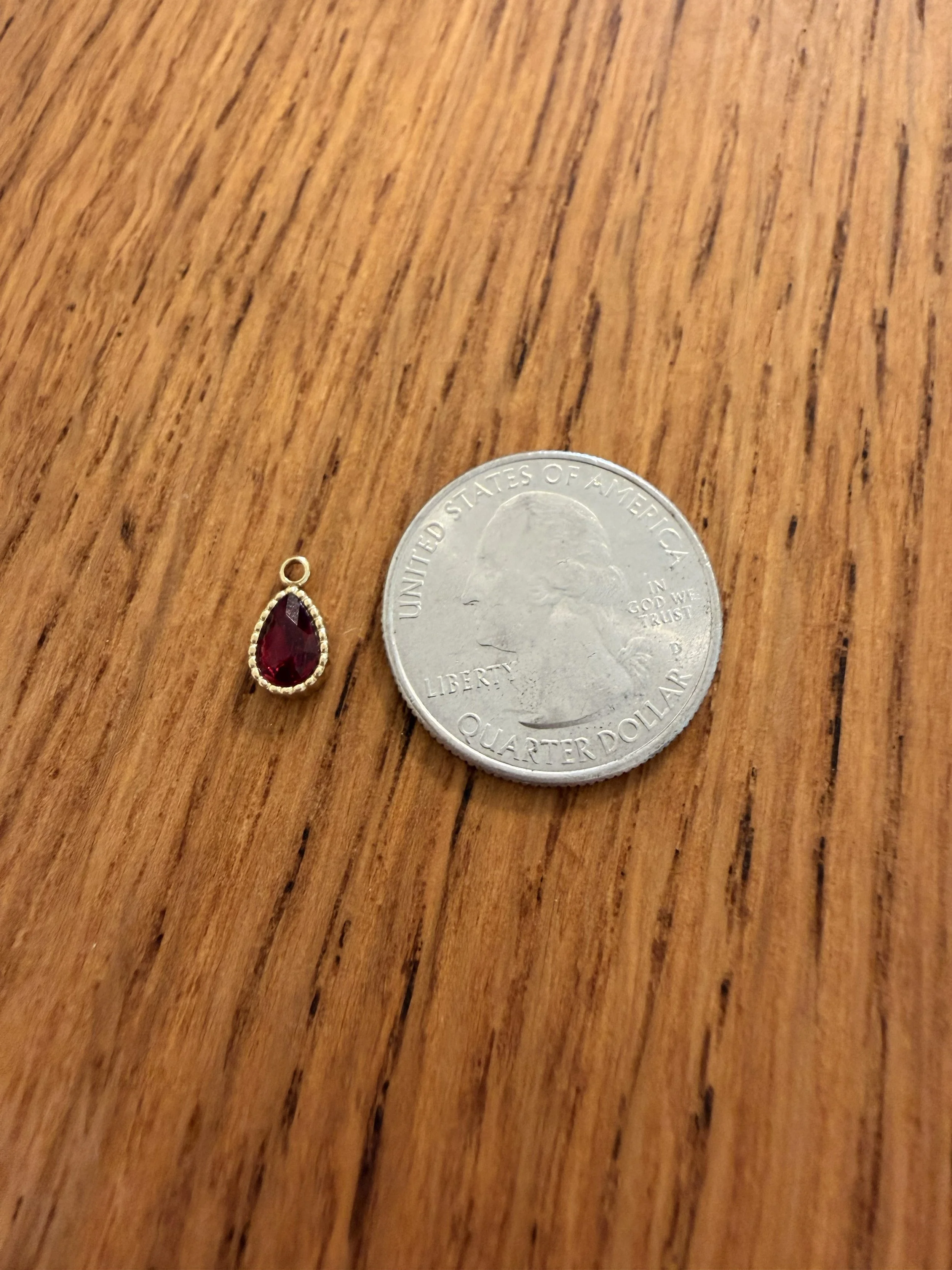 Pear Cut Birthstone Charm for January or July by House of Azelea with quarter on wood countertop