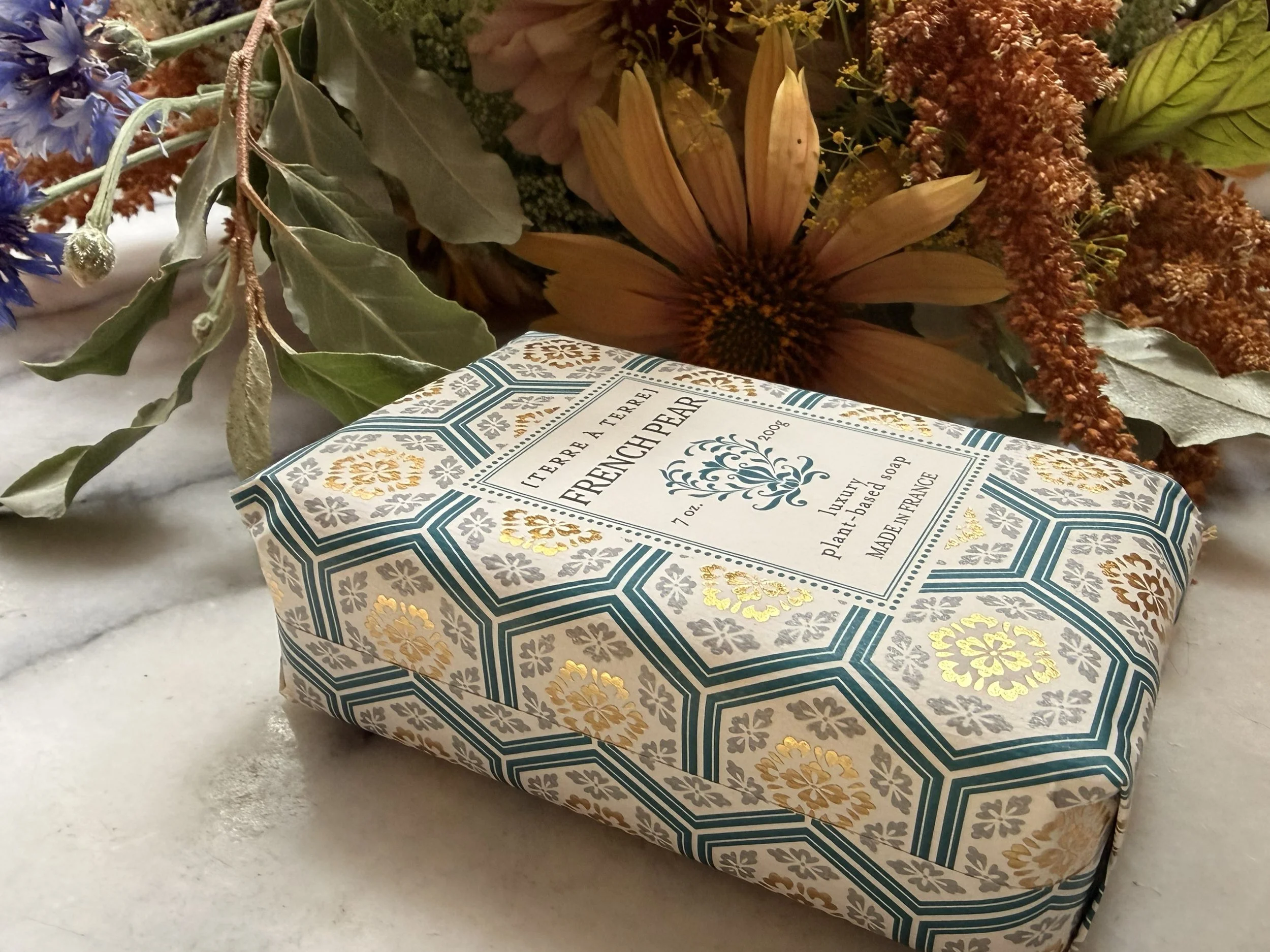 Side view of Terre á Terre French Pear Soap with flowers on marble