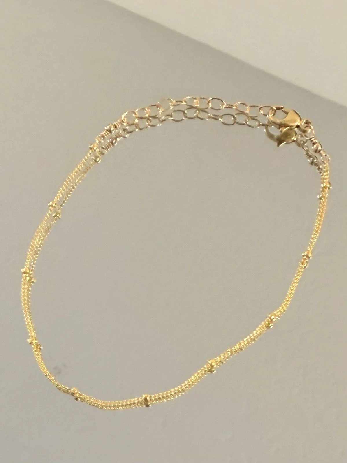 Close-up of Delicate Ball Chain Bracelet by Katie Waltman Jewelry displayed on mirror