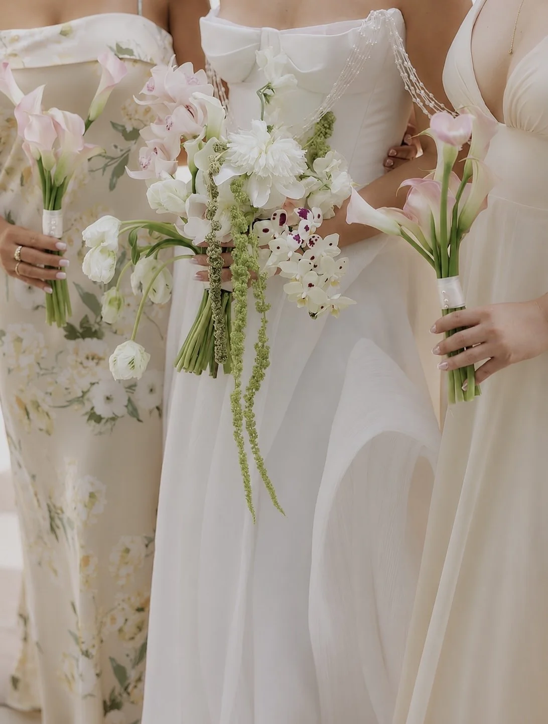 People in wedding dresses holding bouquets of white and pink flowers, standing together at a wedding ceremony.