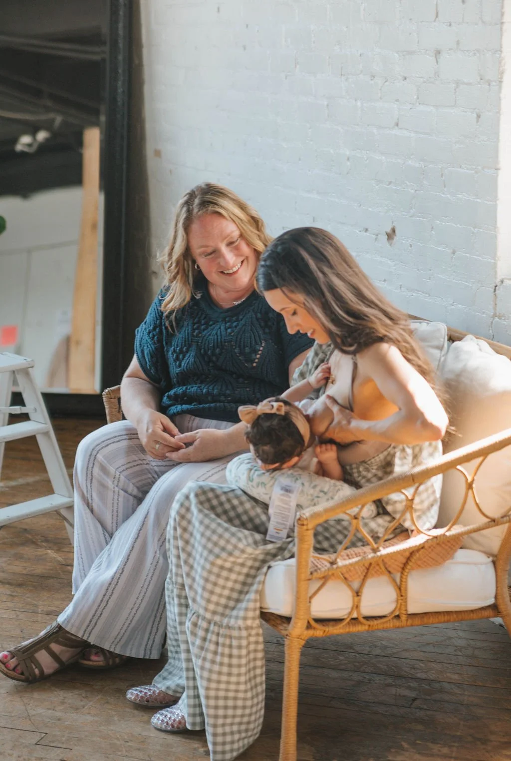 A new mother learns latching techniques with her young infant as a lactation consultant sits near providing support and encouragement.