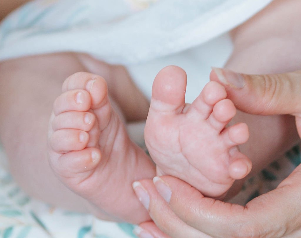 A medical provider holds an infant's feet at a lactation clinic appointment.
