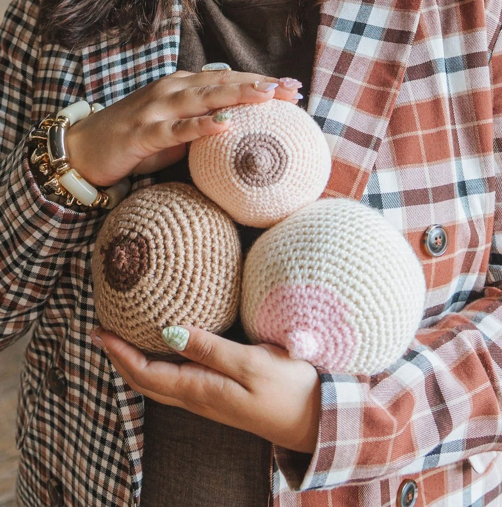 A lactation consultant holds three skin-tone inclusive crocheted lactation nipple aides.