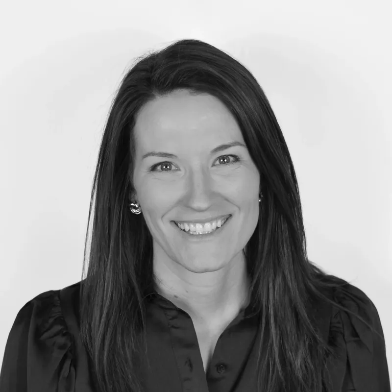 Black-and-white portrait of a smiling woman with long dark hair, wearing a dark blouse and earrings.