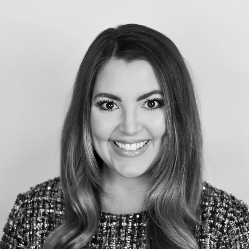 A smiling woman with long, wavy hair in a black and white photograph.