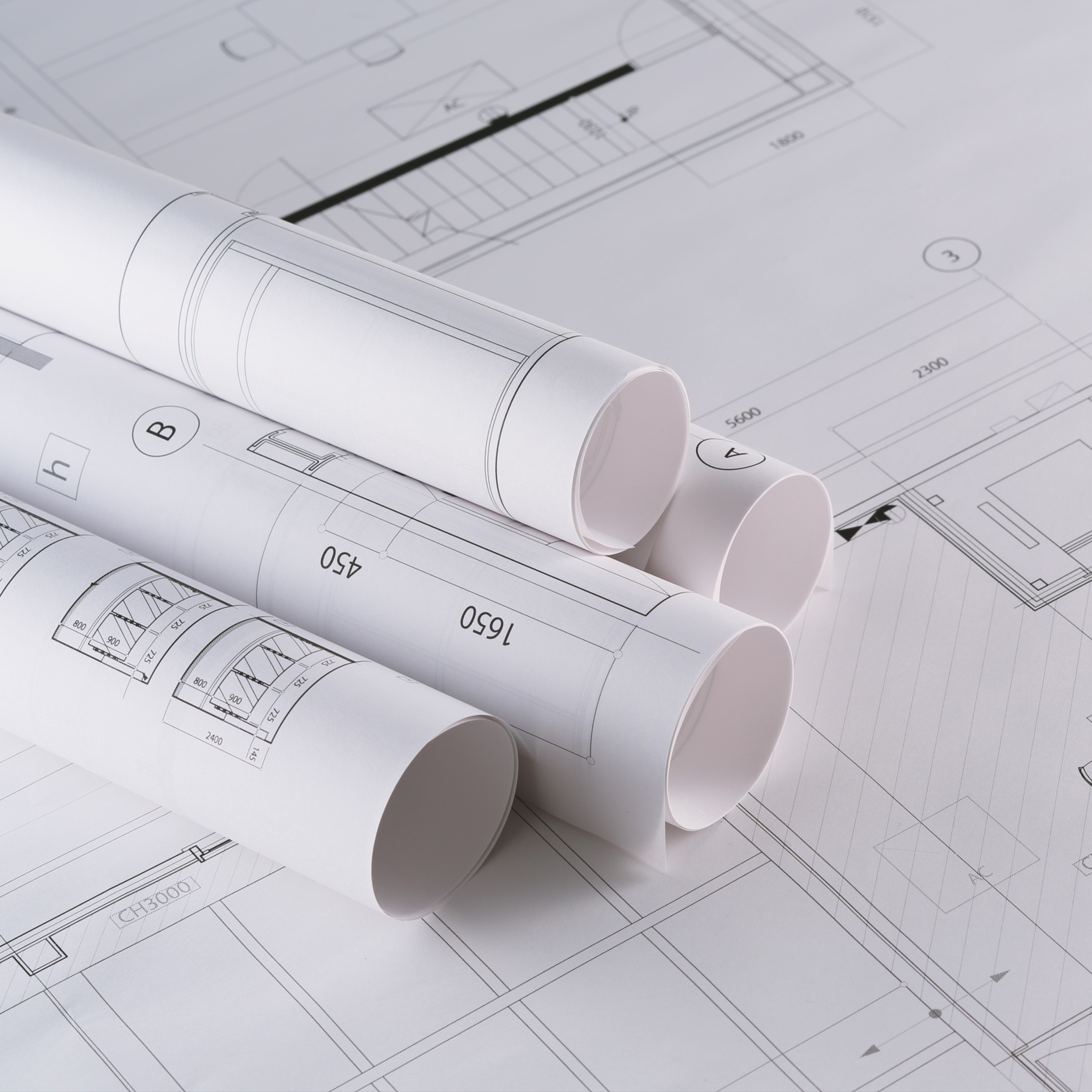 Architectural blueprints and rolled-up drawings on top of a detailed floor plan.