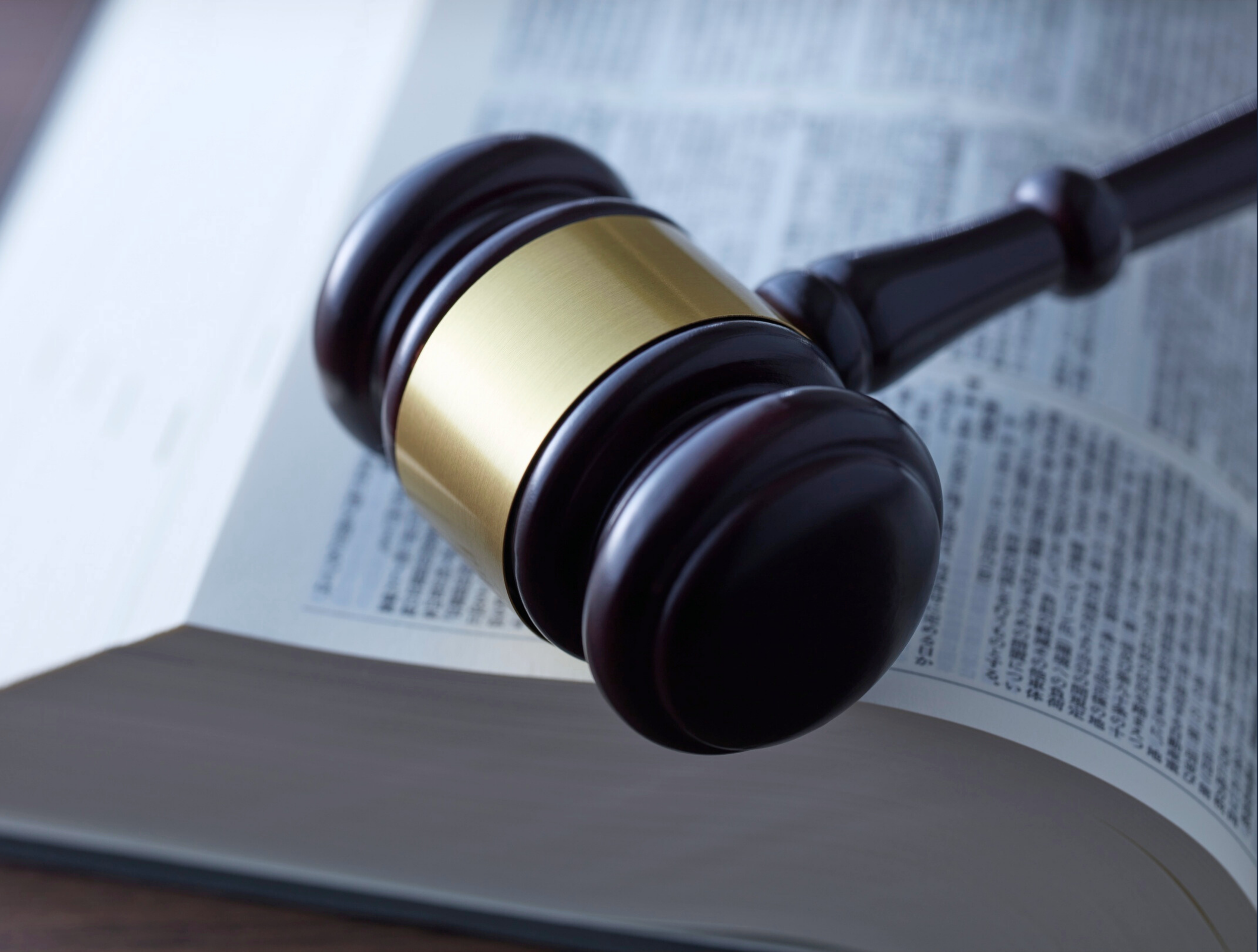 A wooden judge's gavel resting on an open book, with the pages visible.