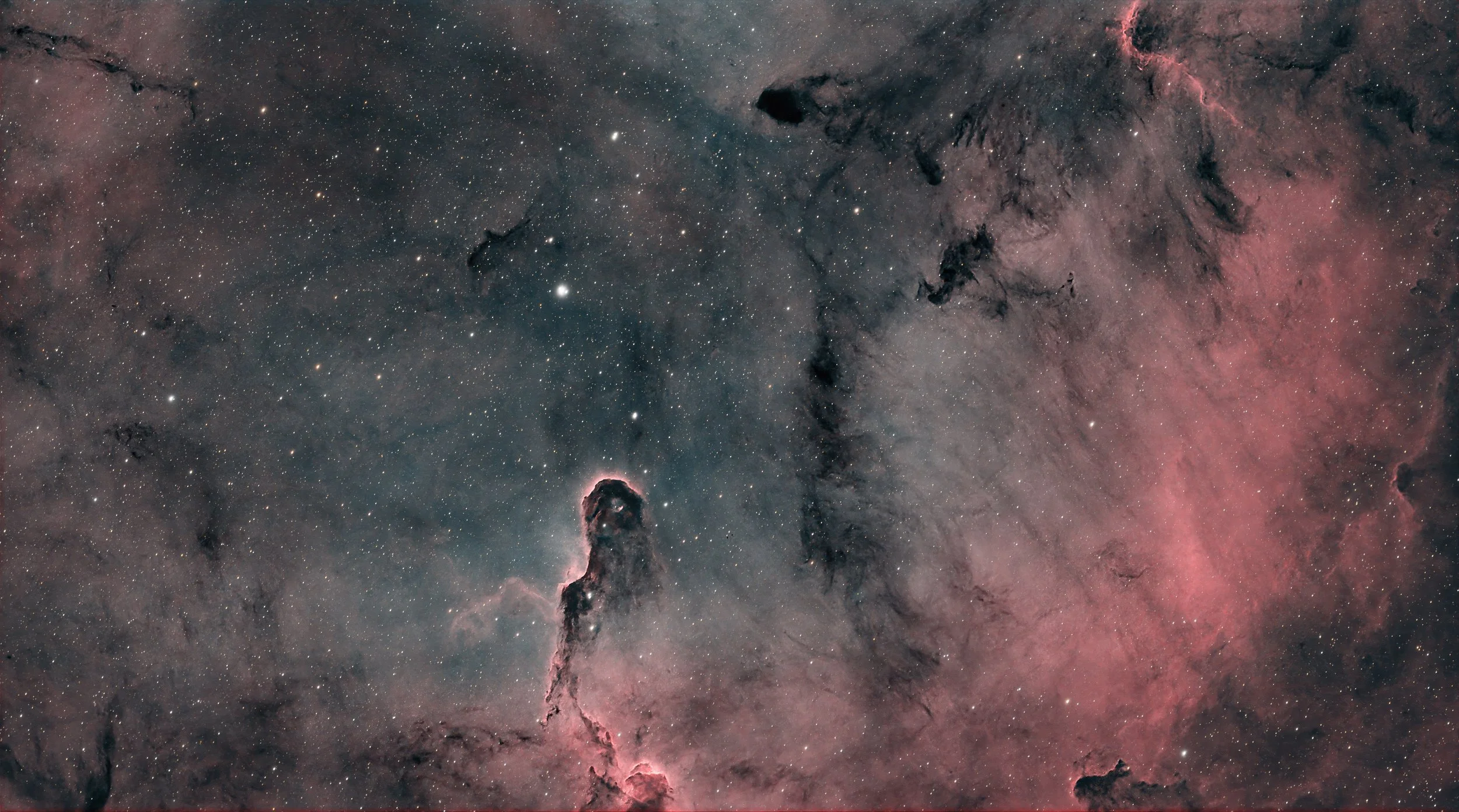 Deep space image of the Orion Nebula showing stars, dark dust clouds, and glowing pink and gray gas formations.