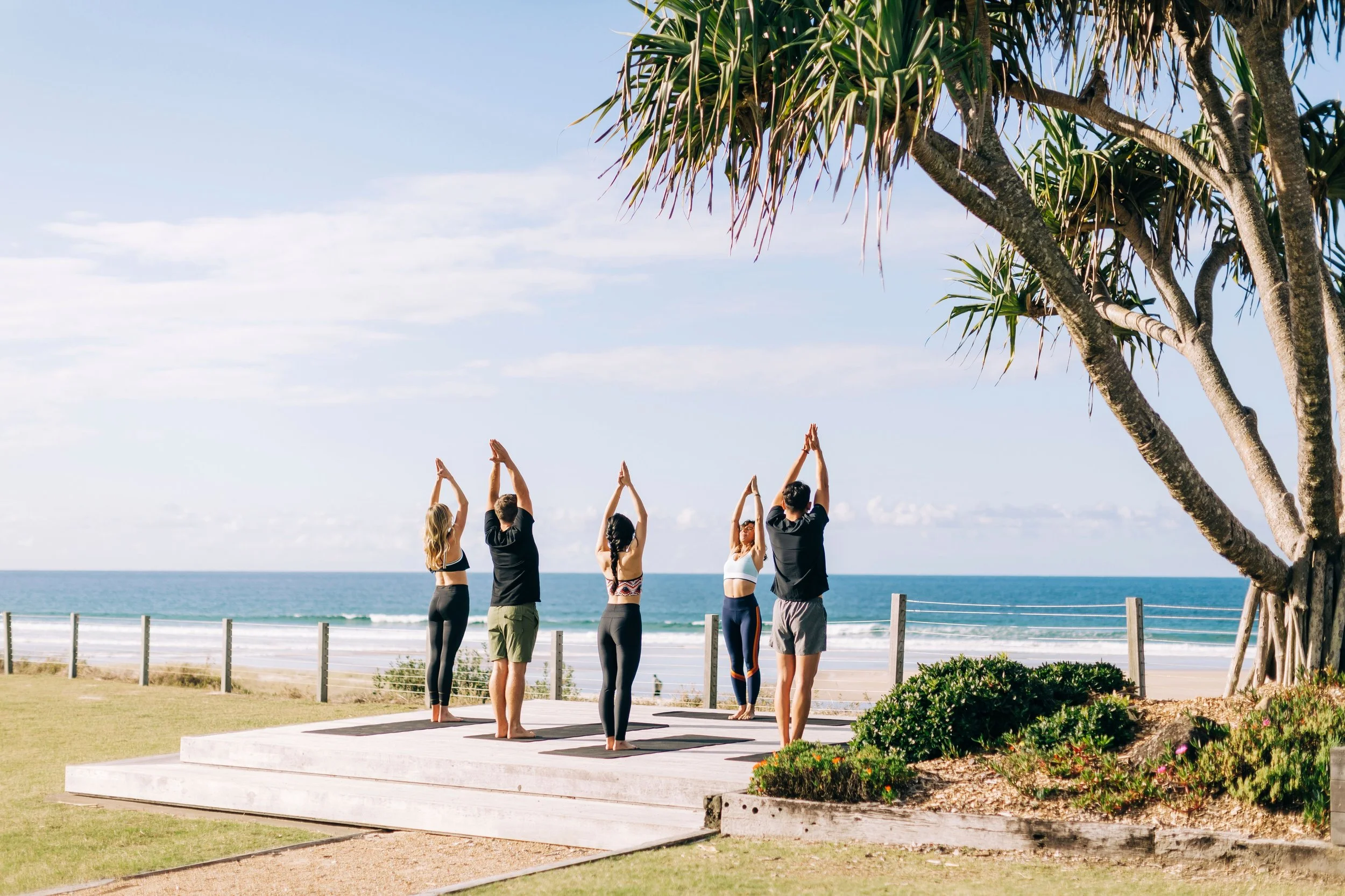 Group of people doing yoga in front of a beach in Byron Bay