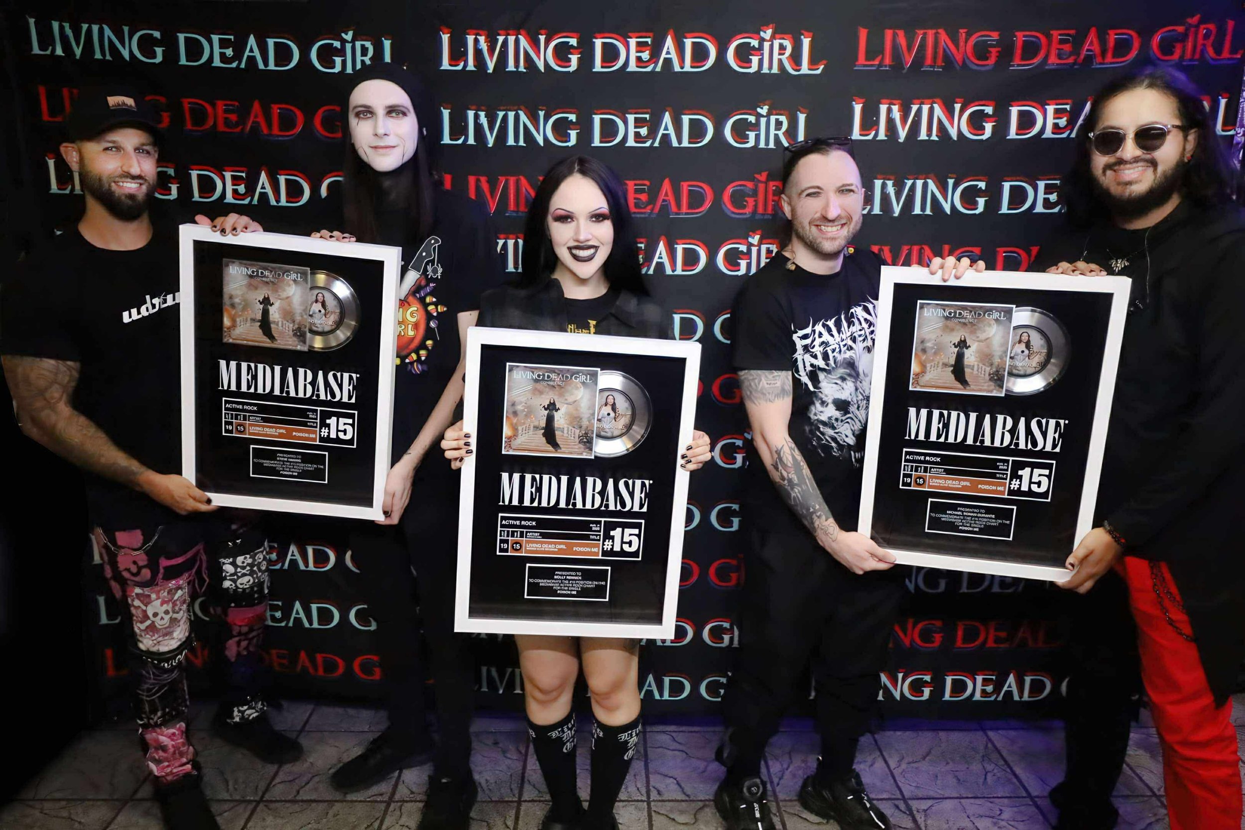 Group of five people celebrating with framed awards in front of a 'Living Dead Girl' backdrop.