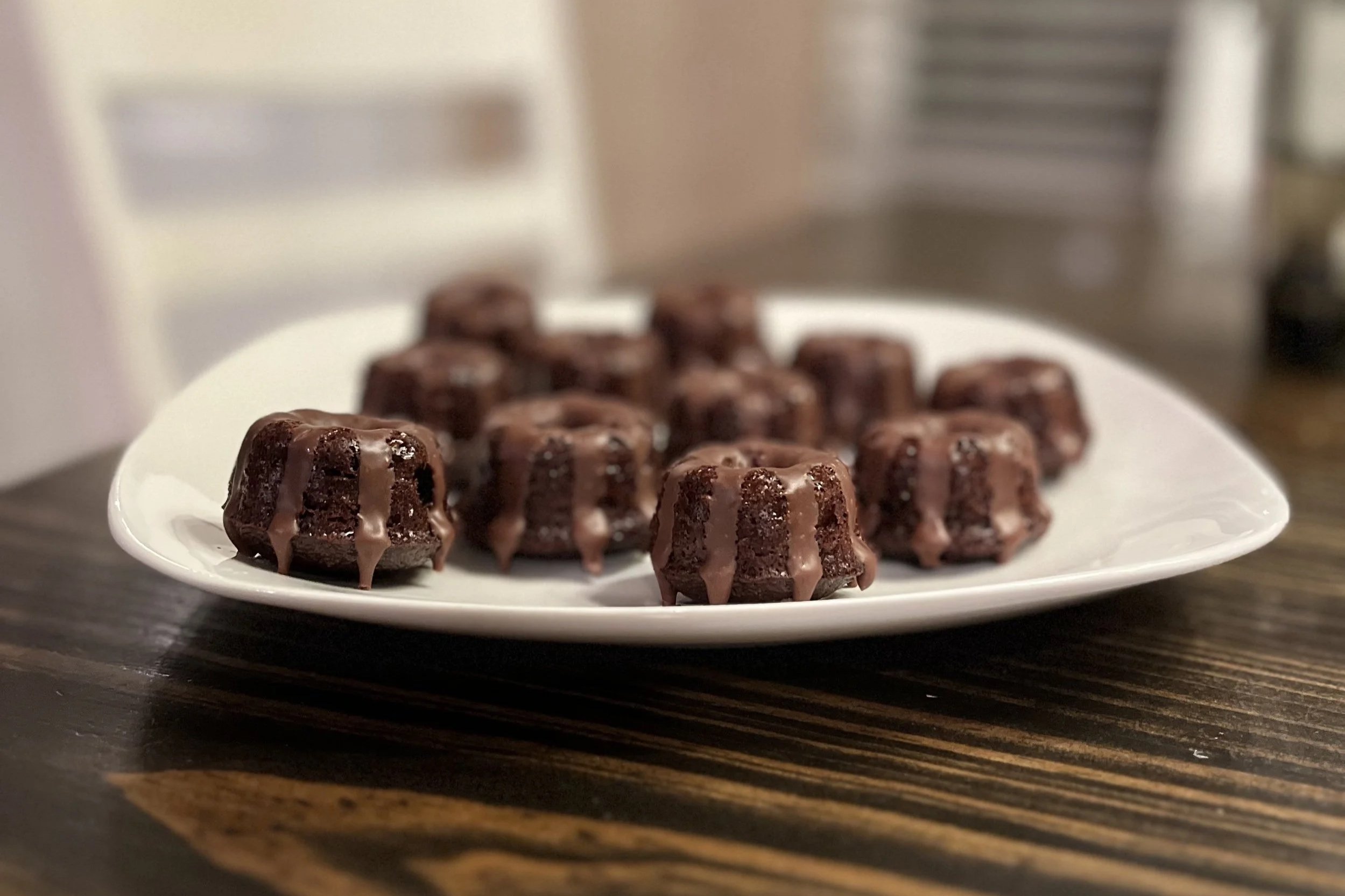 Plate of small chocolate baked desserts with chocolate drizzle