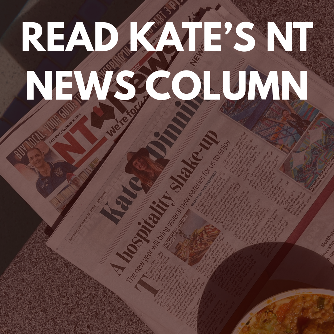 Newspaper articles with headlines about a hospital shake-up and a sports figure on the front page, placed on a textured surface. Part of a pizza is visible in the bottom corner.