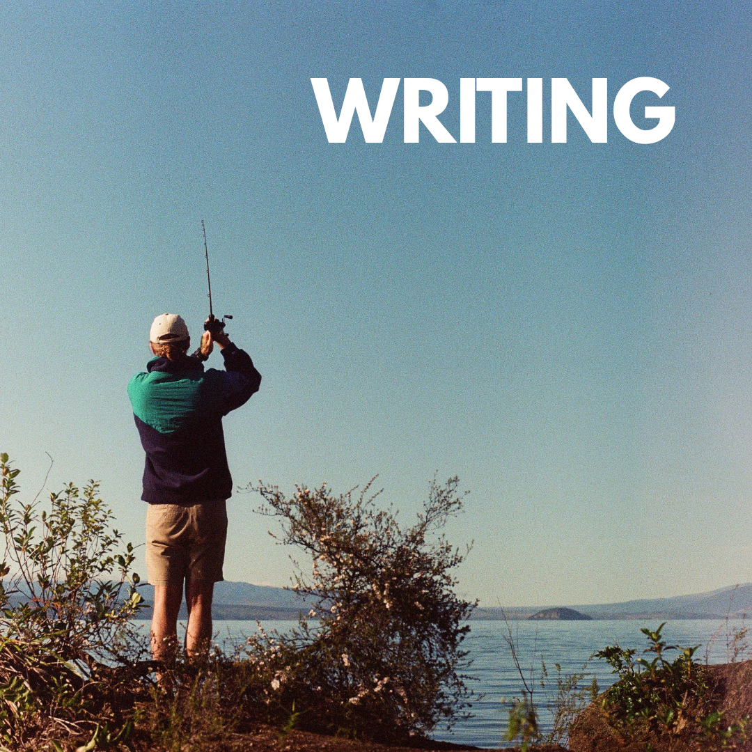 Person standing on rocky shore fishing in a body of water under a clear sky, with the word 'WRITING' in large white letters at the top.