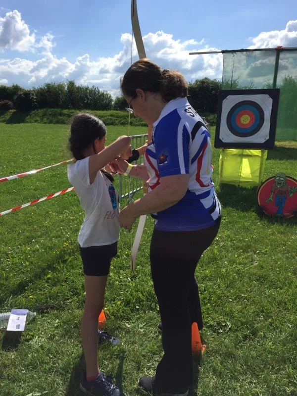Une femme et une jeune fille participent à une activité de tir à l'arc en plein air.