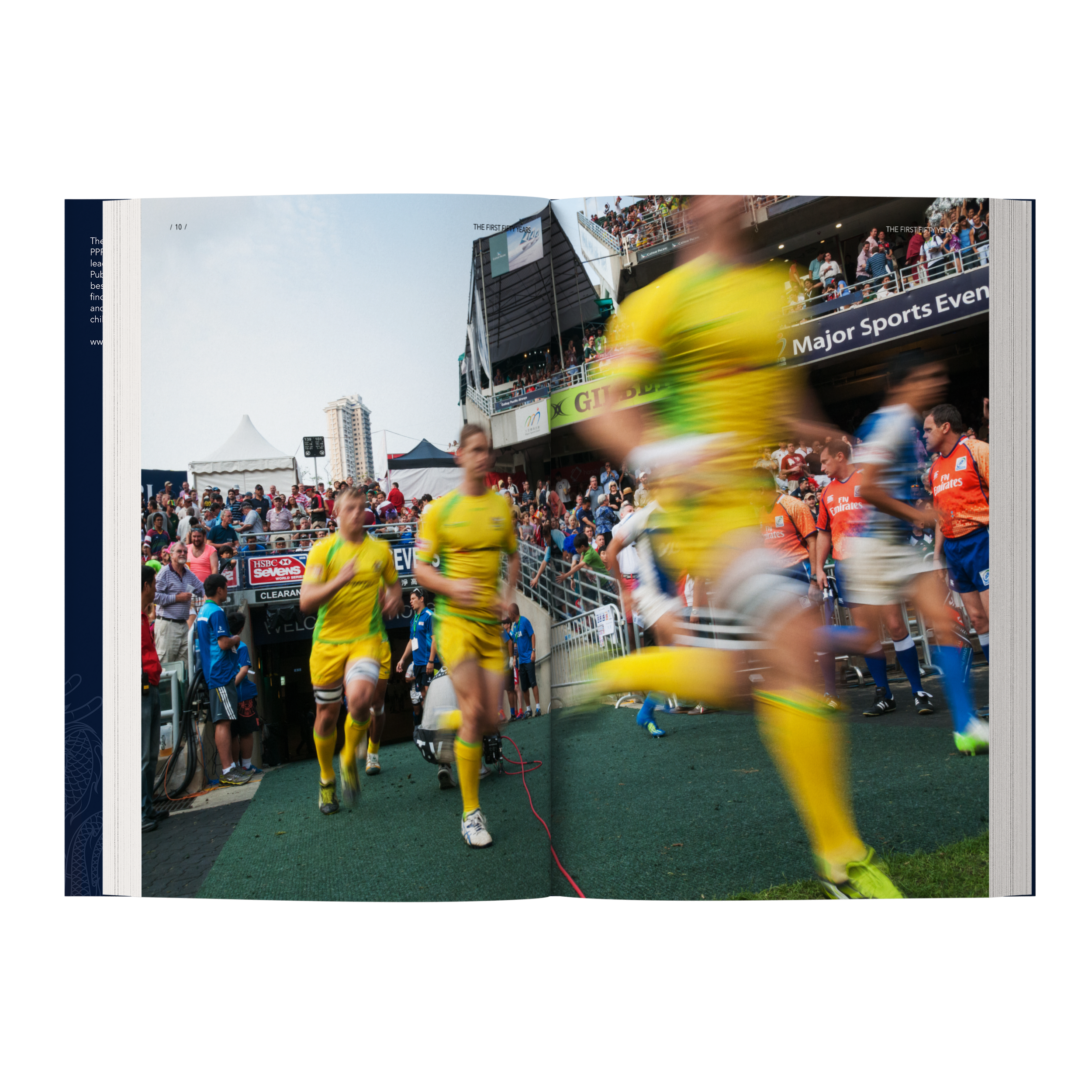 Athletes in yellow uniforms running onto the field at a sports stadium, with spectators and team members in the background. Image from mock-up of The First Fifty Years.