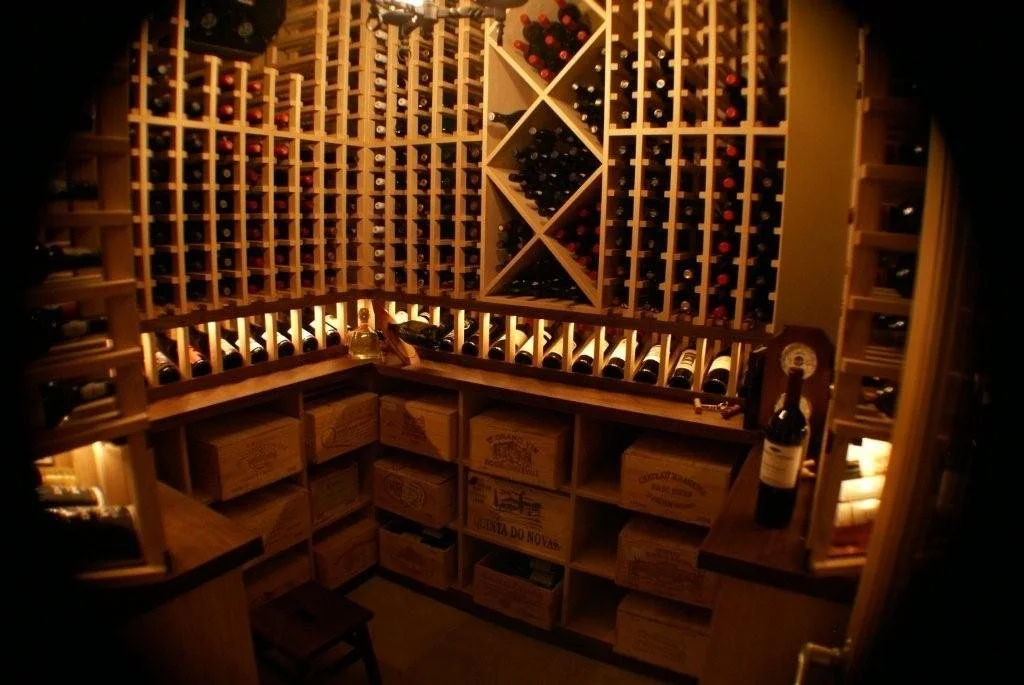 A cozy wine cellar with wooden wine racks filled with bottles, soft warm lighting.  Offering multiple storage facings and displays.