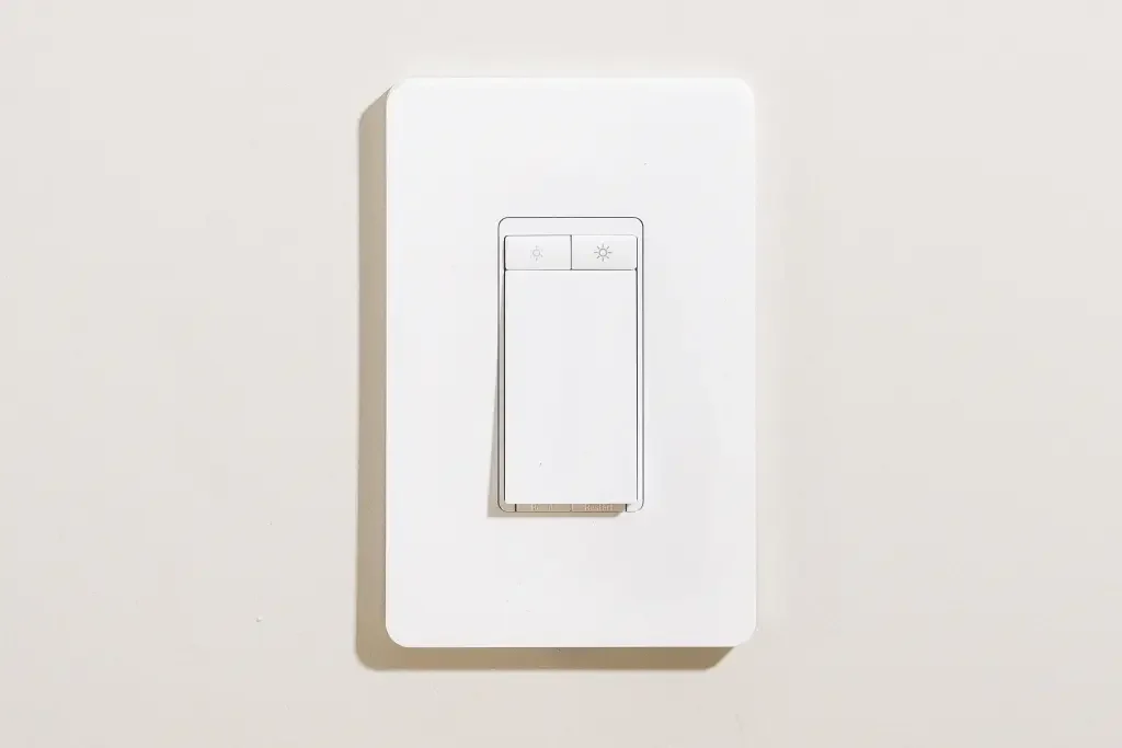 A white light switch with two buttons installed on a white wall.