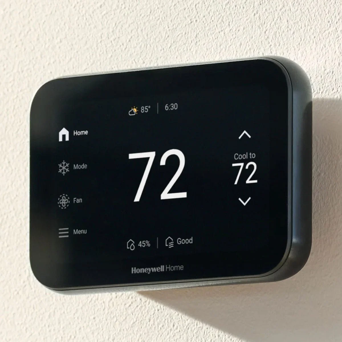 Smart thermostat mounted on a wall displaying a temperature of 72 degrees Fahrenheit, with options for home, mode, fan, and menu on the screen.