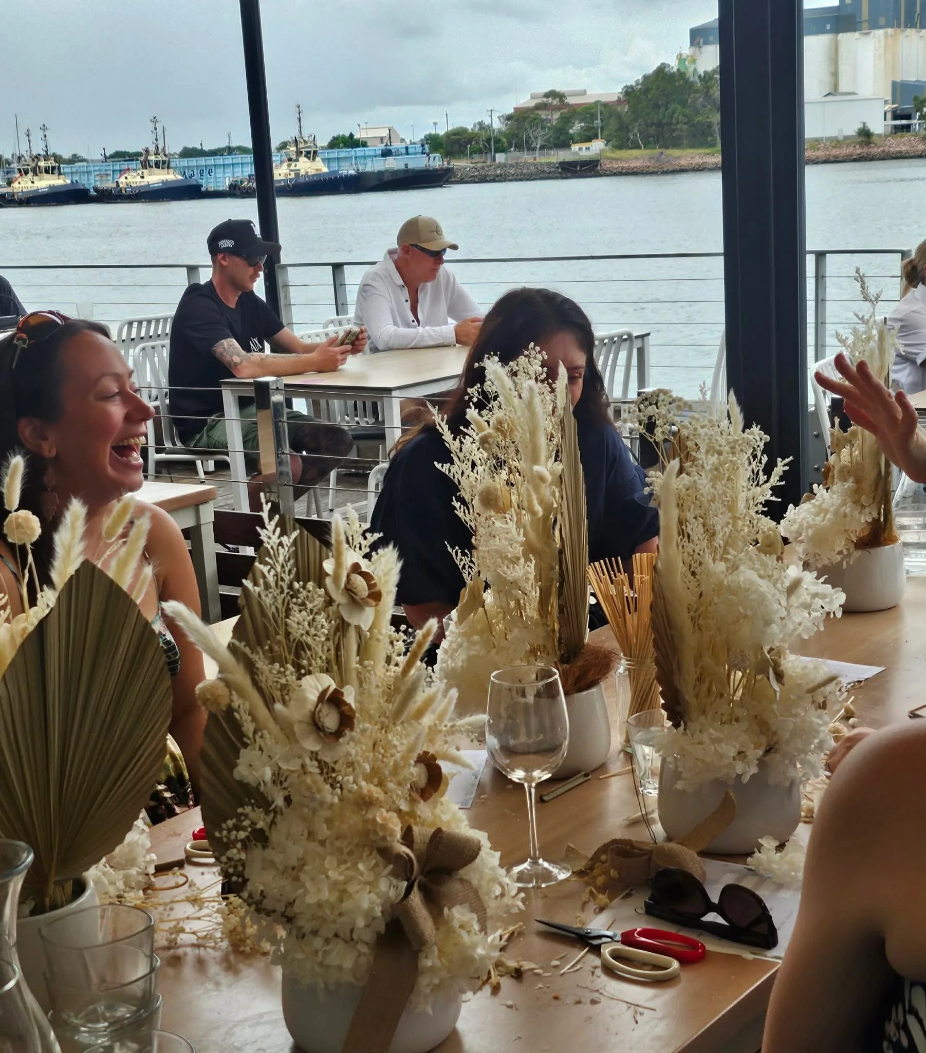 Friends creating preserved floral arrangements during a hens party workshop.