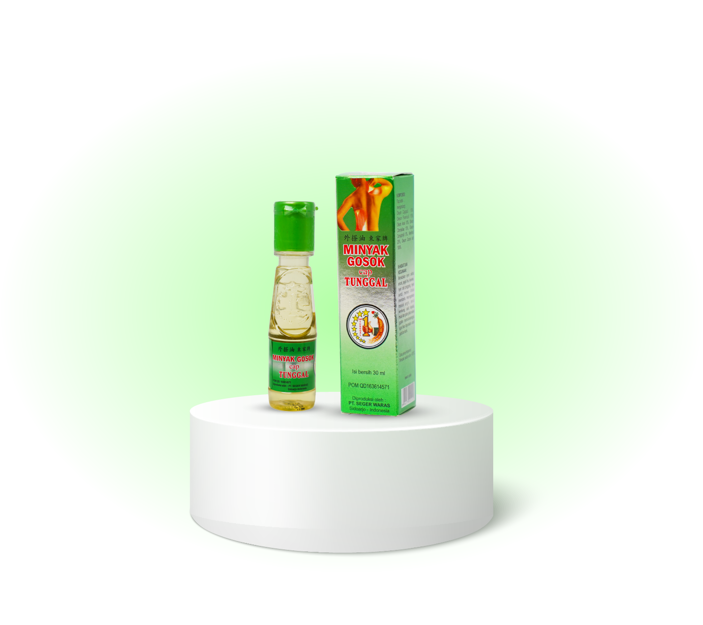 A small bottle of herbal oil labeled 'Minyak Gosok Cap Tunggul' next to its box packaging, both placed on a round white platform against a split black and green background.