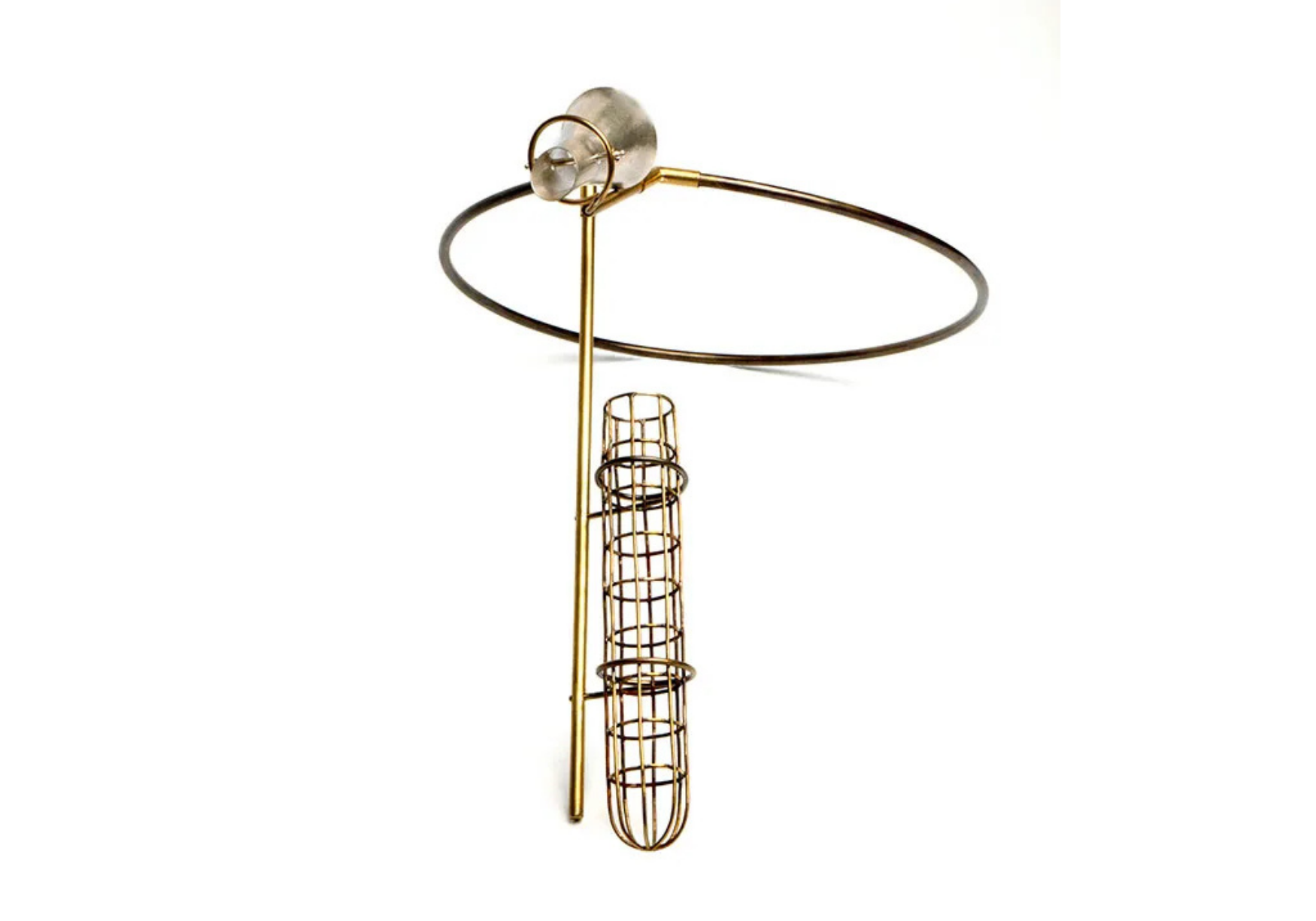 A metallic sculpture with a circular ring at the top, attached to a vertical pole, with a cylindrical cage-like structure hanging below, all set against a plain white background.