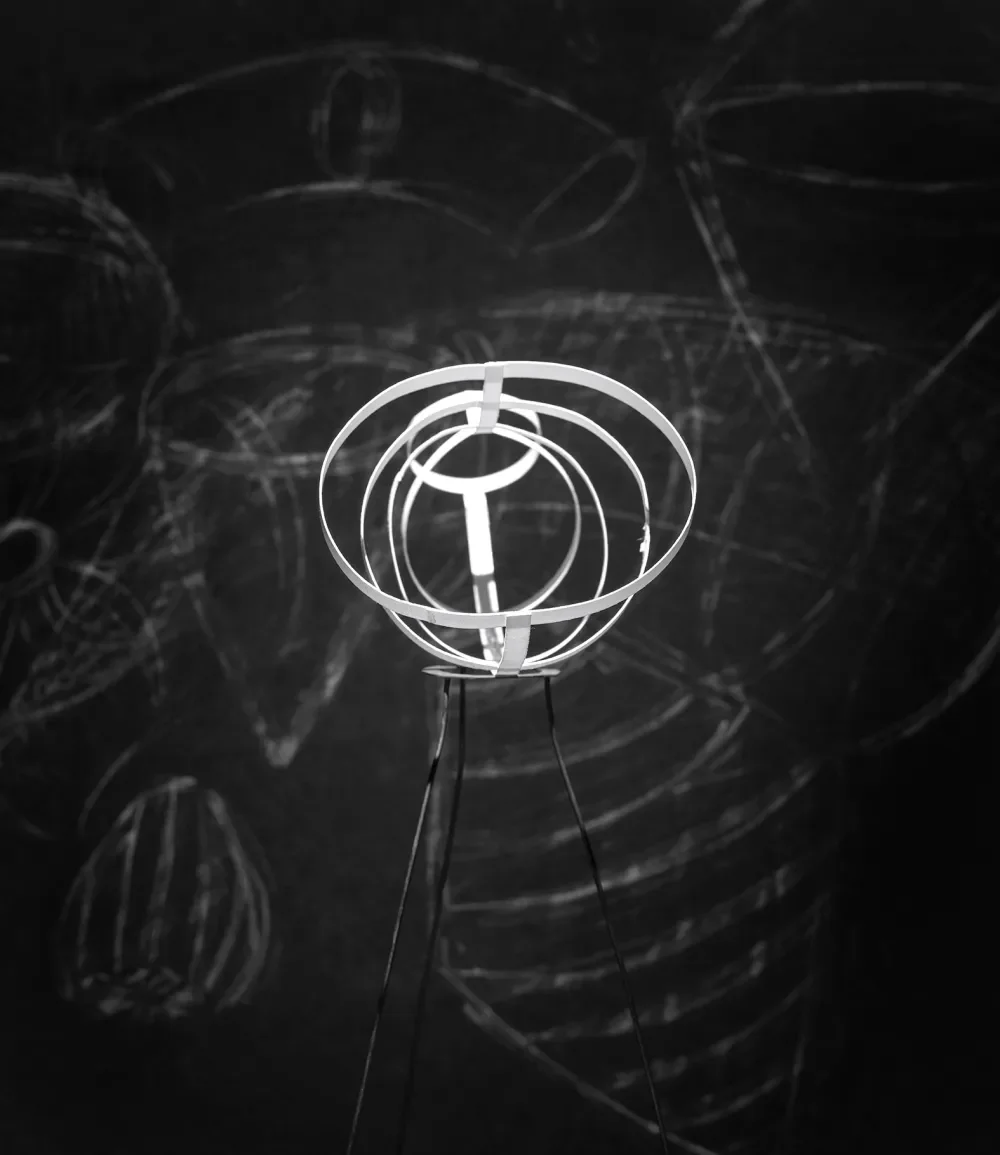 A modern desk lamp with a spherical, geometric design casting shadows on a dark wall.