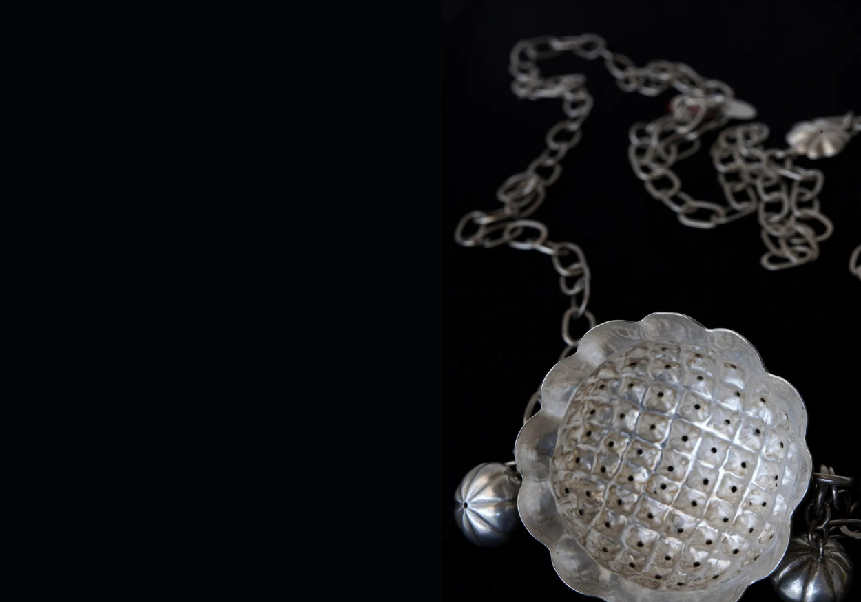 Silver jewellery with a pendant necklace, featuring a large, round, detailed, scalloped-edged piece with a grid of small holes.