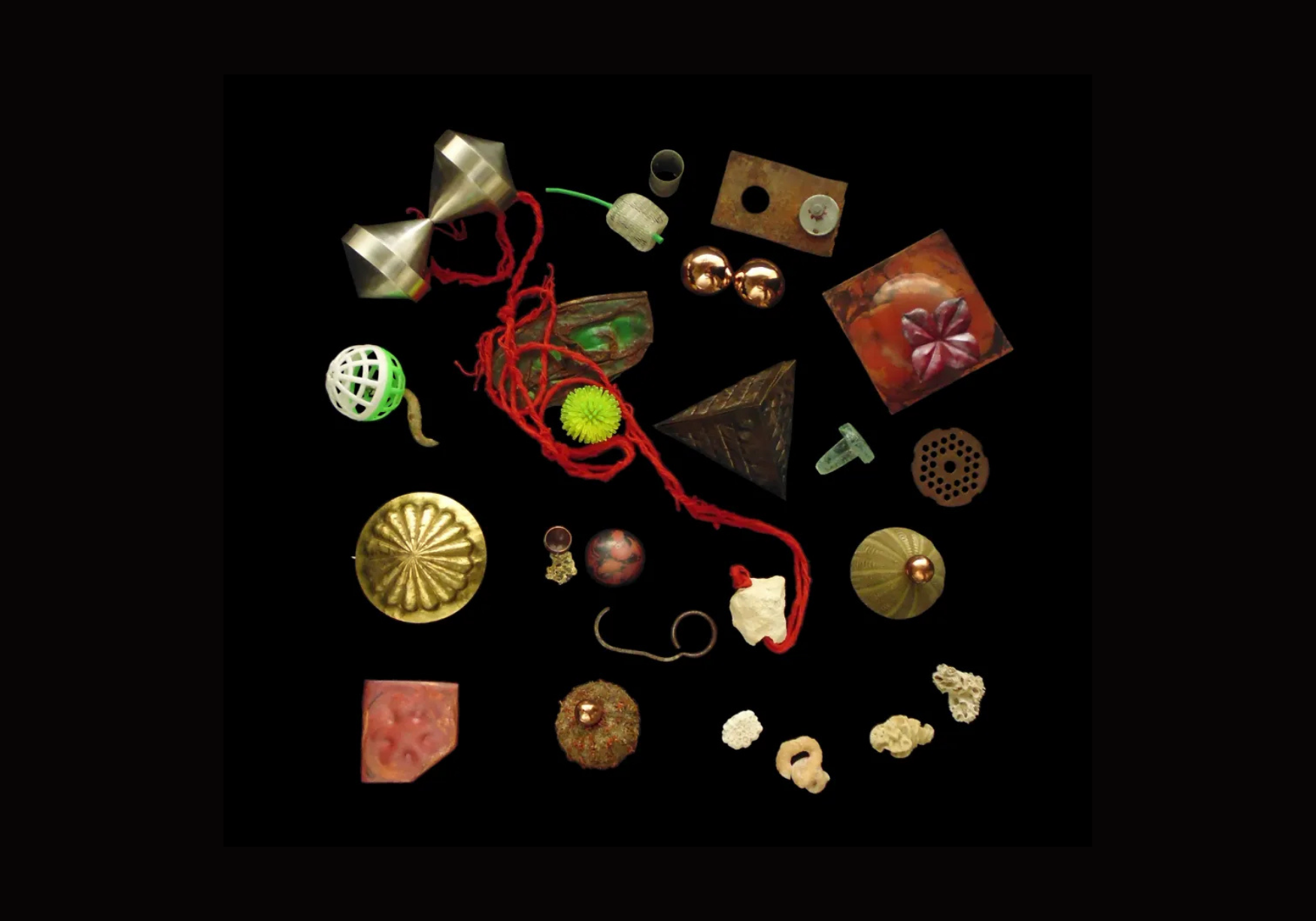 Assorted small decorative objects including shiny metallic balls, patterned cubes, and textured spheres scattered on black background.
