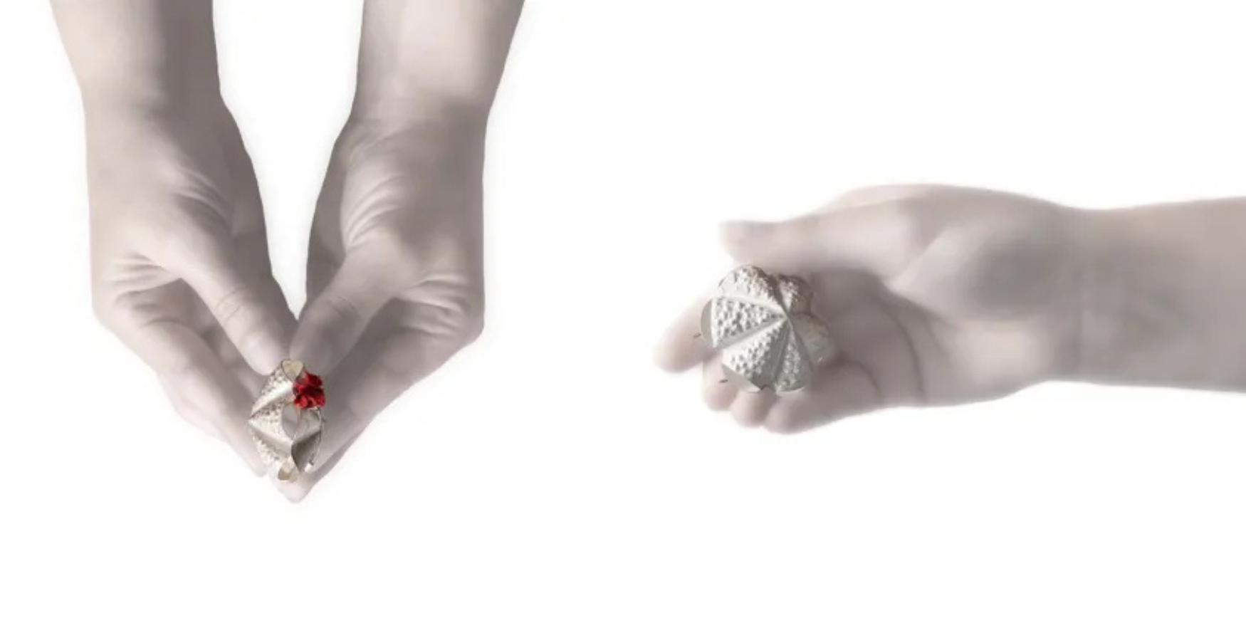 Two hands holding folded paper hearts with small red details, opaquely lit against a white background.