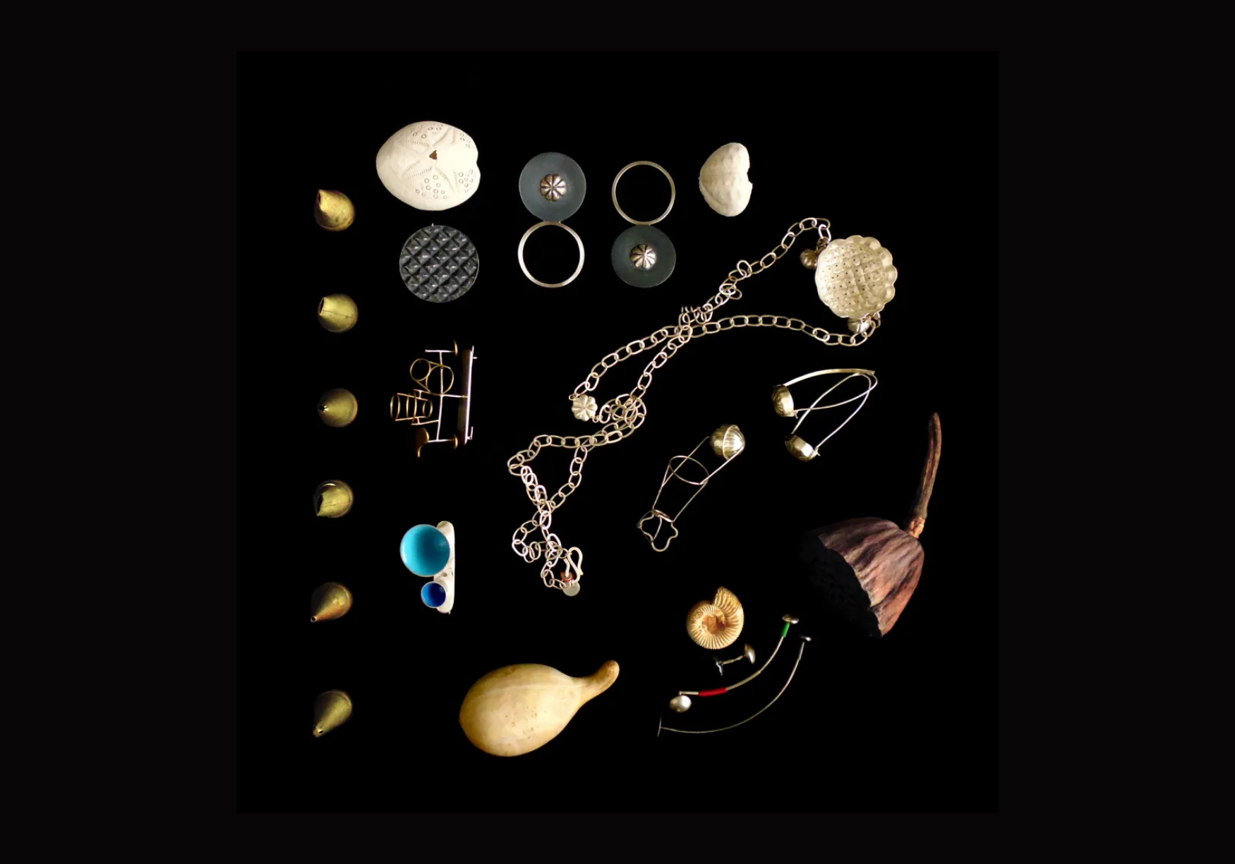 A collection of jewellery and small objects on a black background, including necklaces, rings, earrings, shells, and a small seashell with a pointed end.