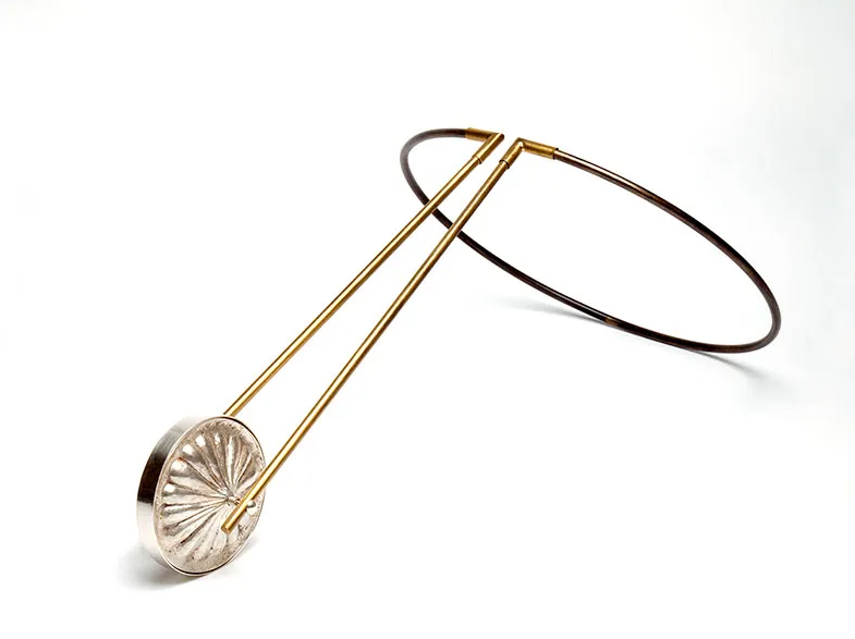 A modern decorative sculpture resembling a pair of tongs with gold handles and silver circular ends, attached to a thin black loop.