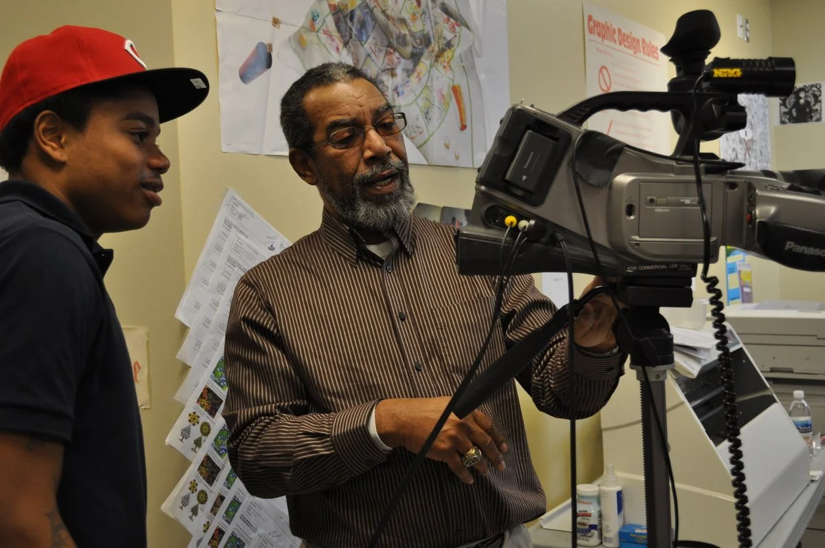 Two men working together with a professional video camera in an office environment.
