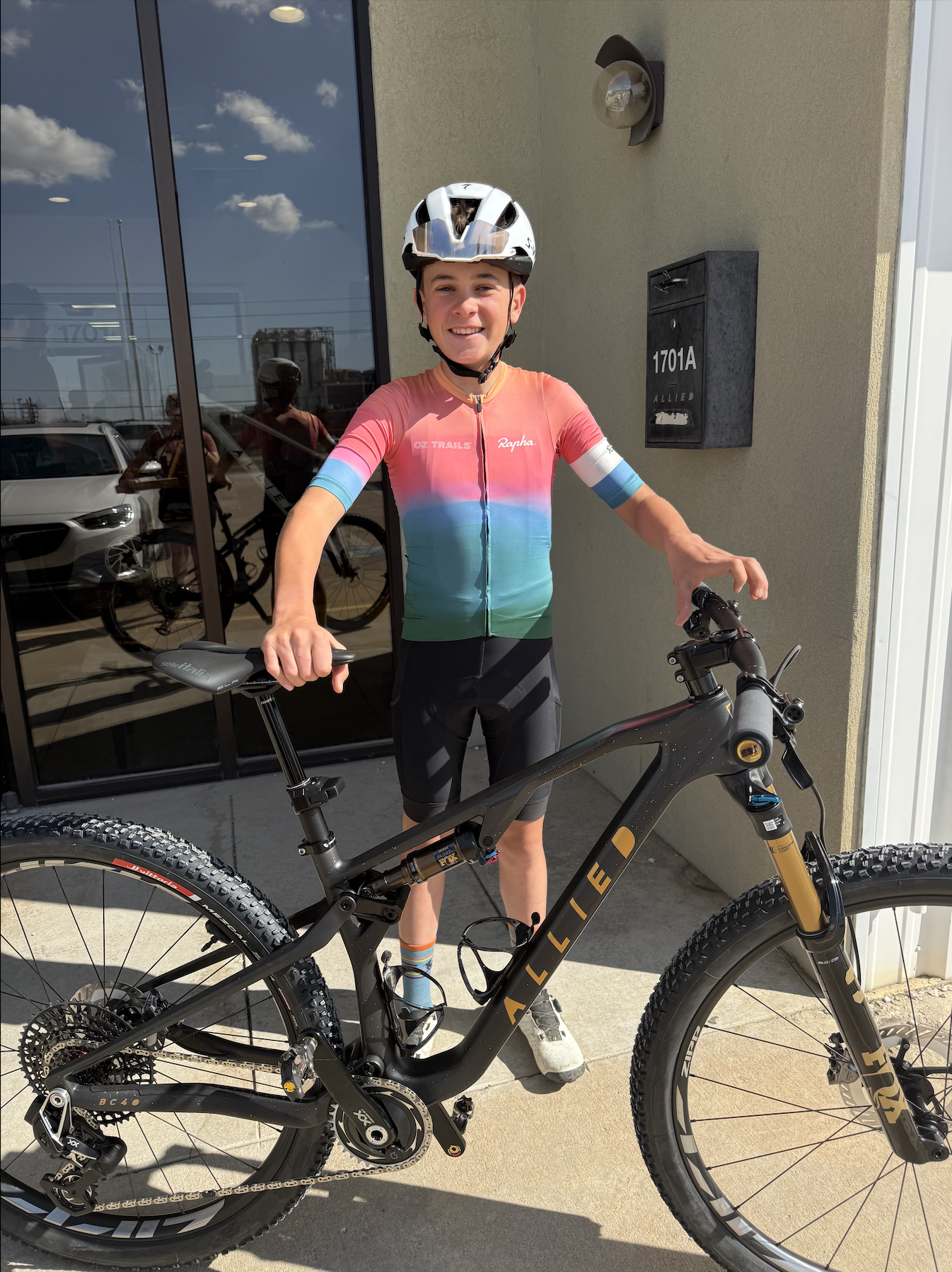 Boy with bike stands in front of office building door.