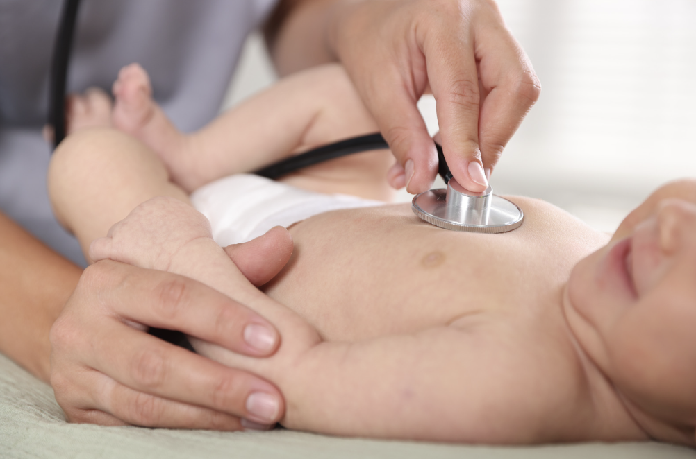Doctor examines a baby using a stethoscope on the baby's chest.