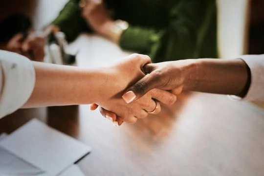 Two people shaking hands in a professional setting.