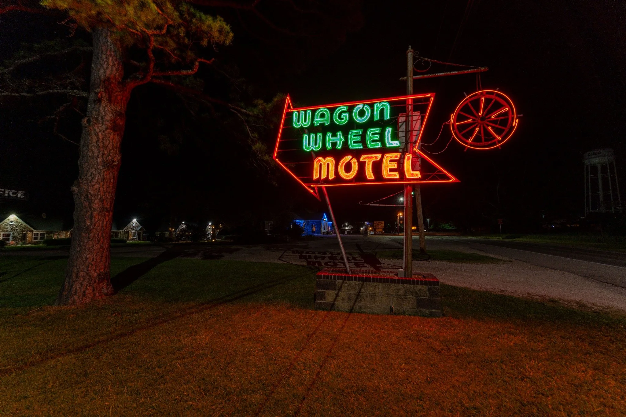 The Wagon Wheel Motel’s vintage neon arrow sign glowing at night beside Route 66.